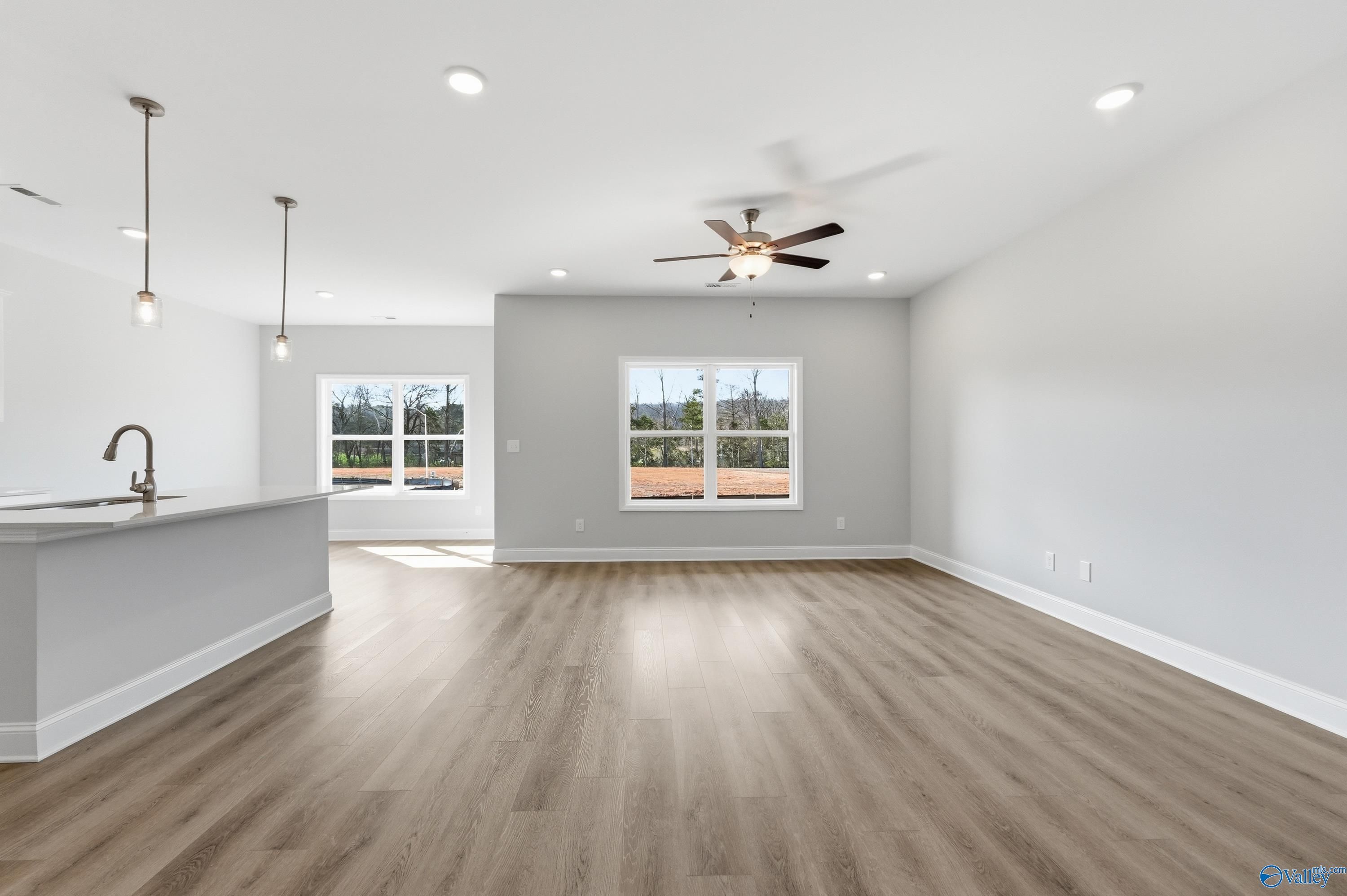 Bright open-concept kitchen with white cabinets, stainless sink, island, and large windows in The Asheville C home, Huntsville, Alabama