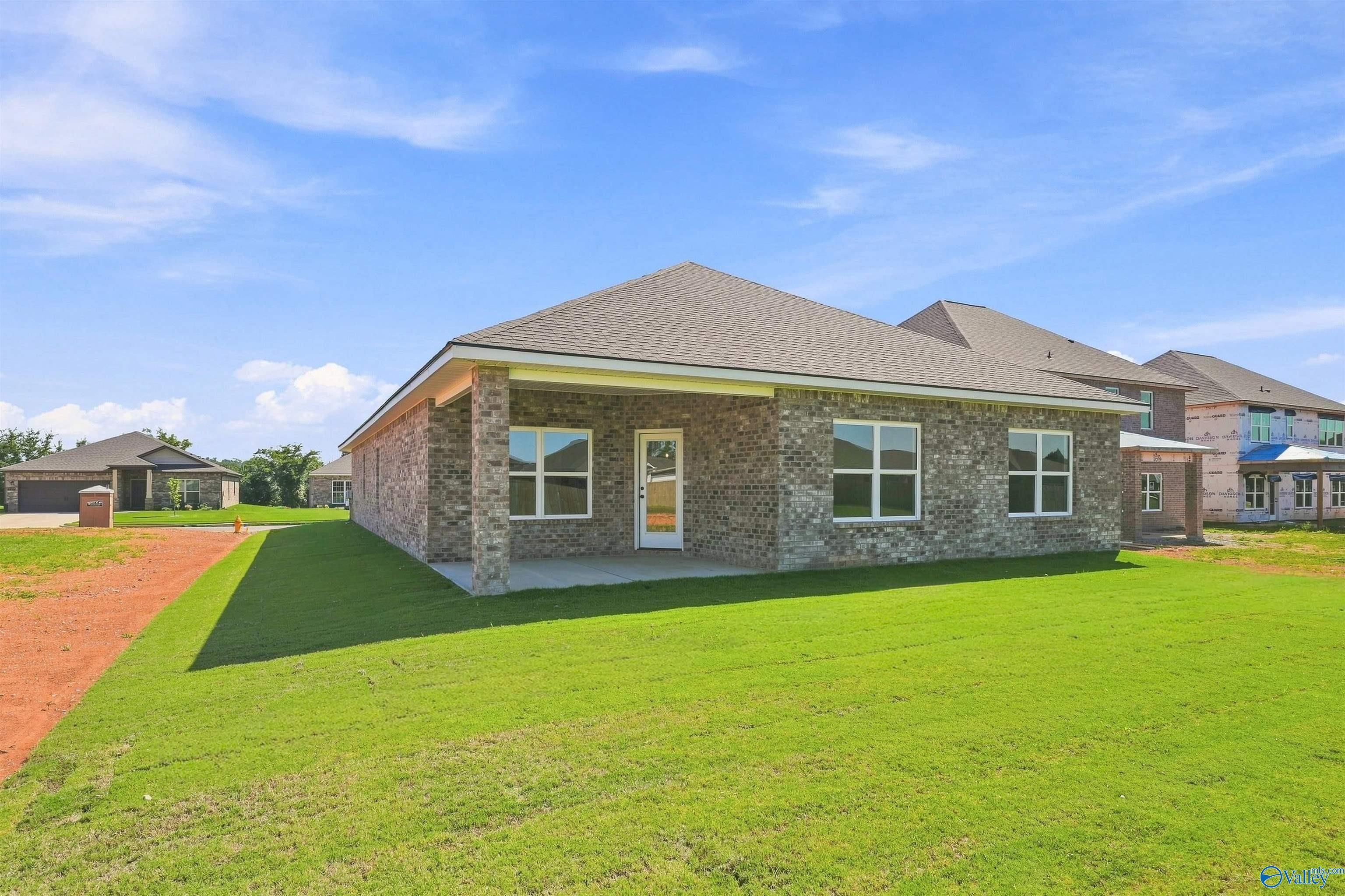 Brick single-story new construction home with covered patio and green lawn in Davidson Homes' Ivy Hills community, Toney, Alabama