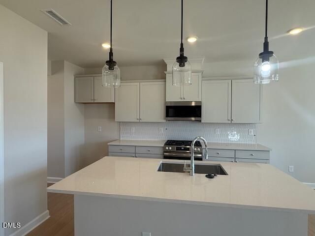 Modern white kitchen with large island sink, stainless steel appliances, subway tile backsplash in Davidson Homes The Willow D, Zebulon NC