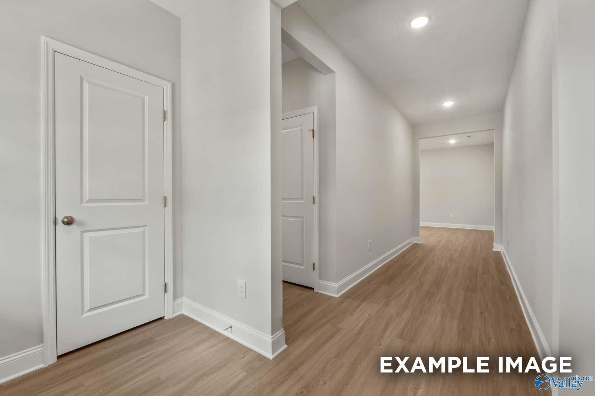 Bright hallway with white doors, recessed lighting, and hardwood floors in The Camilla B 3-bedroom home, Hartselle, Alabama