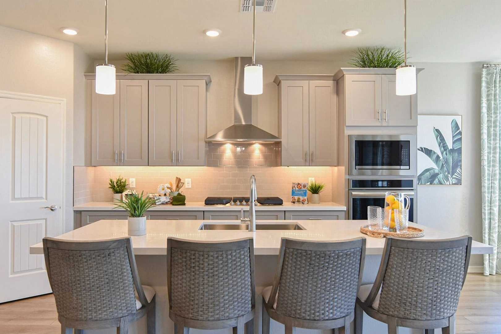 Spacious modern kitchen at North Ridge at Pronghorn Ranch in Prescott Valley AZ with white cabinets, large center island, stainless appliances, tropical decor