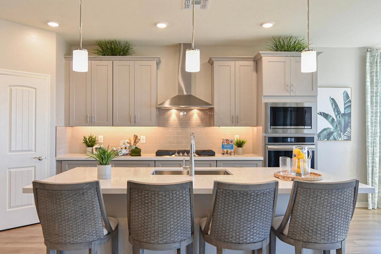 Spacious modern kitchen at North Ridge at Pronghorn Ranch in Prescott Valley AZ with white cabinets, large center island, stainless appliances, tropical decor