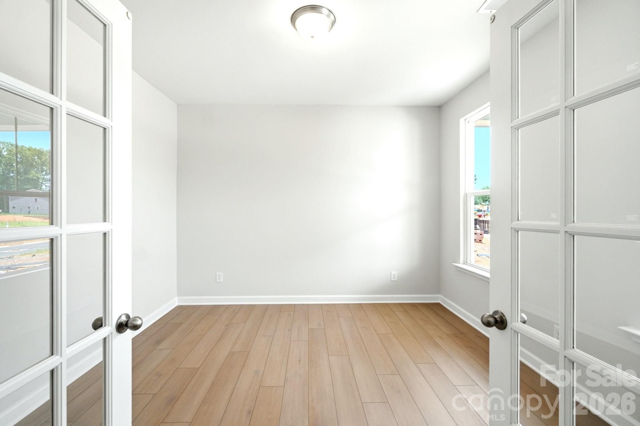 Bright home office or flex room with French doors and wood-look flooring in The Magnolia B plan at Windgate, Mooresville.