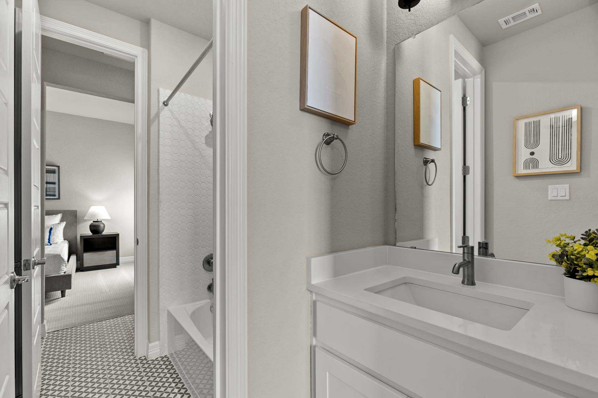 Spacious master bathroom in The Summerlin B with white subway tile shower, modern vanity sink, mirrors, and adjacent bedroom view