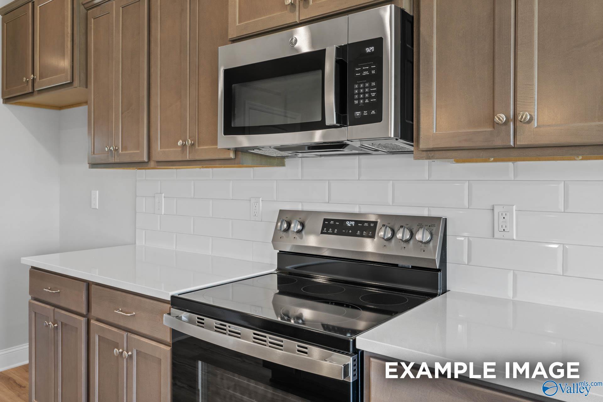 Modern kitchen with white quartz counters, stainless steel range and microwave, shaker cabinets, subway tile in Davidson Homes The Shelby B, New Market, AL