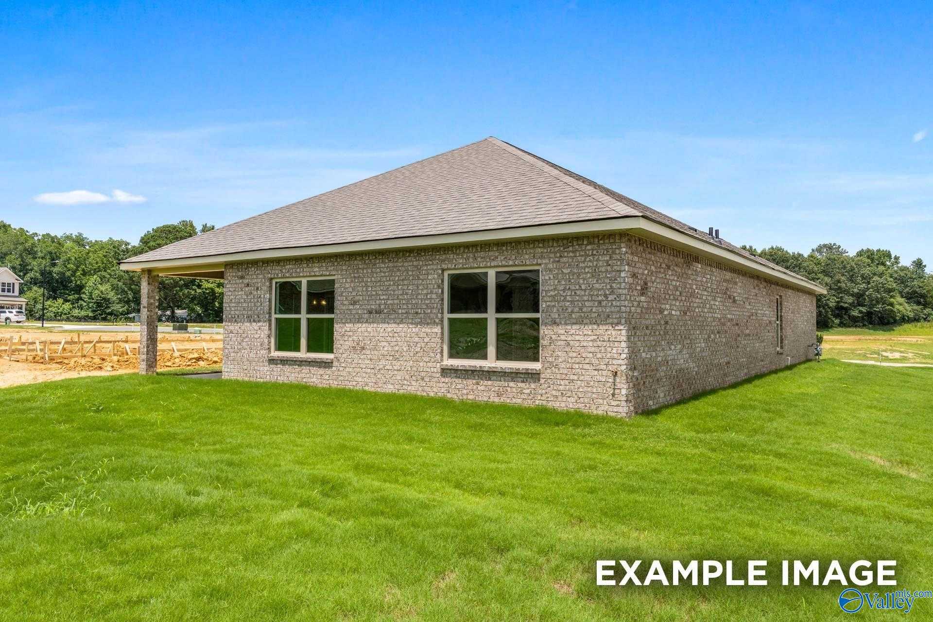 Brick 1-story home exterior with gabled roof, double windows, covered garage, and green lawn in The Highlands, Arab, Alabama