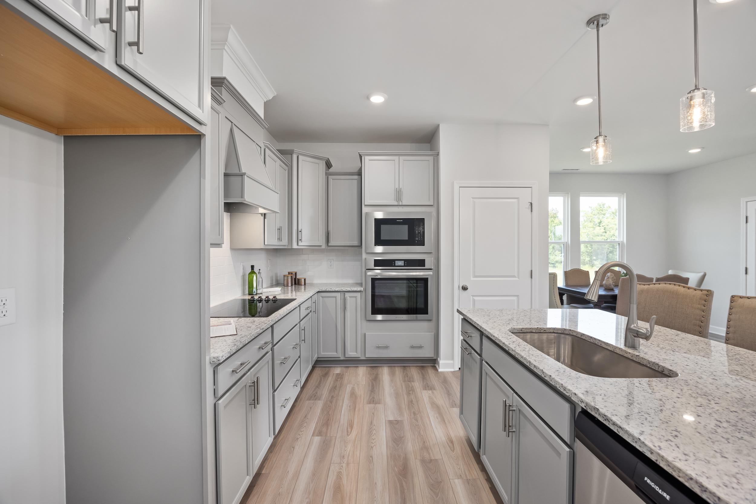 Spacious modern kitchen in The Daphne D by Davidson Homes featuring gray shaker cabinets, quartz island sink, and open dining nook in Mooresville NC