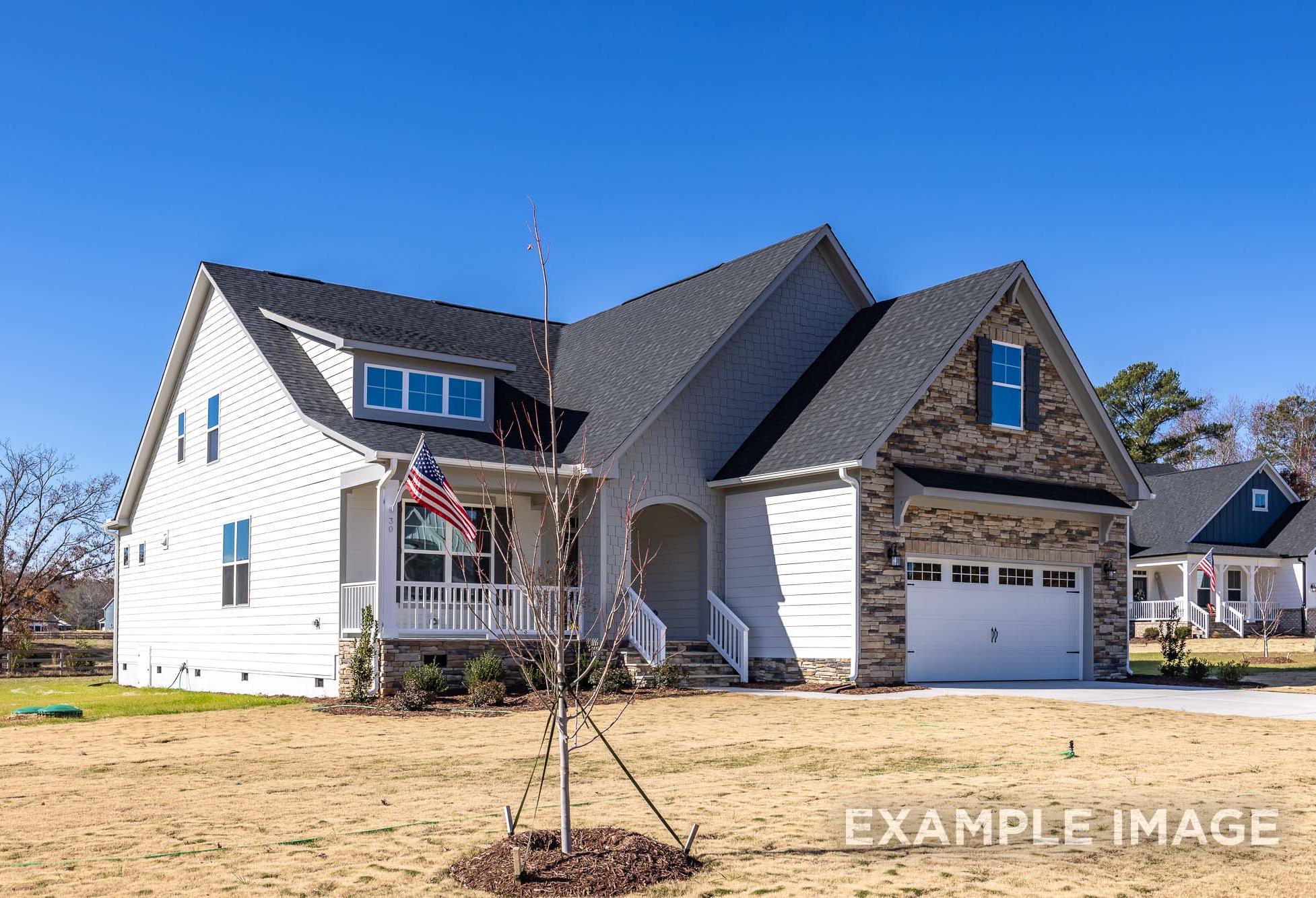 Two-story Cypress II home by Davidson Homes in Angier NC with white siding, stone accents, gray roof, flag porch, and 2-car garage