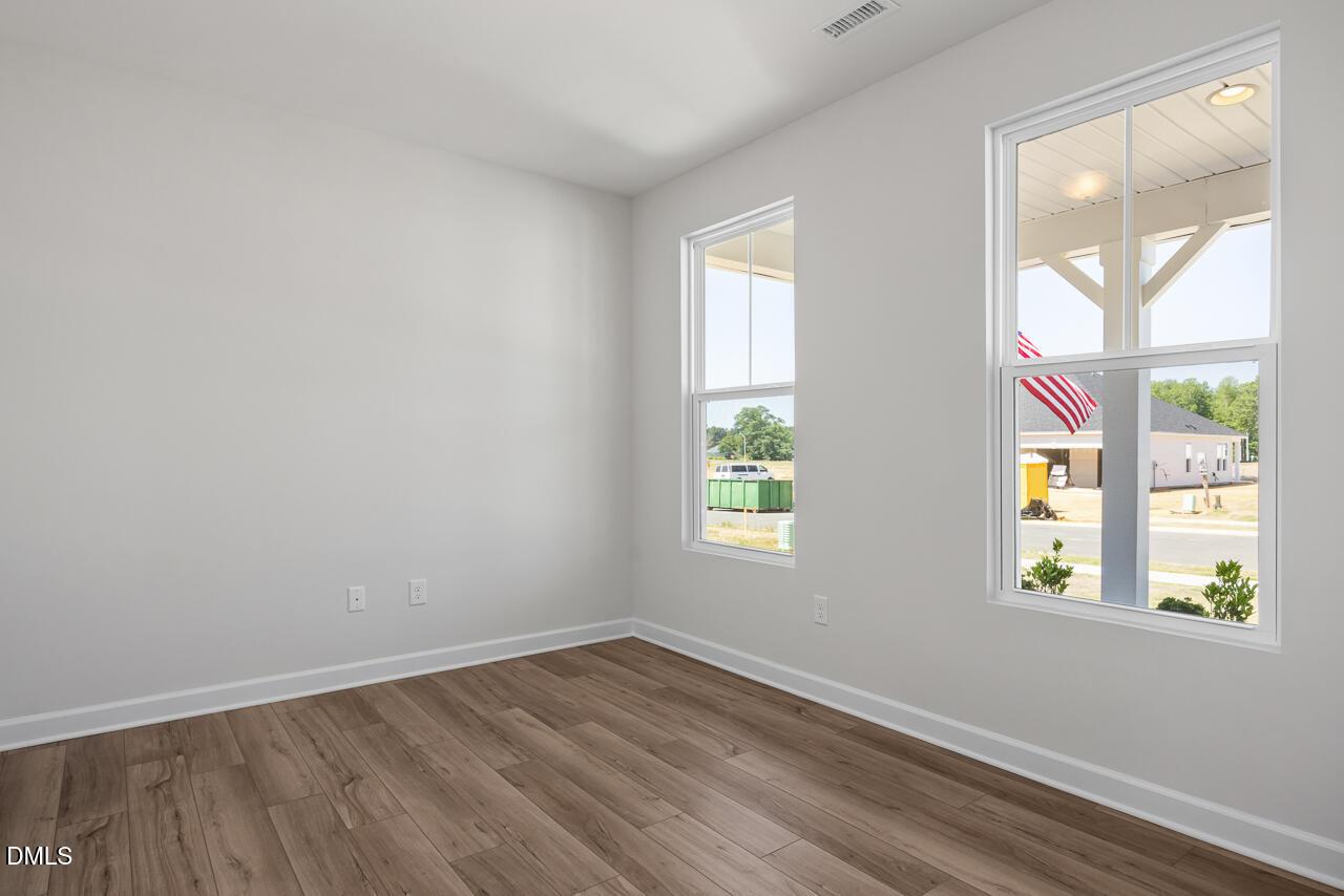 Bright bedroom with wood-look flooring and natural light in The Chestnut B floor plan at Retreat at North Main, Lillington.