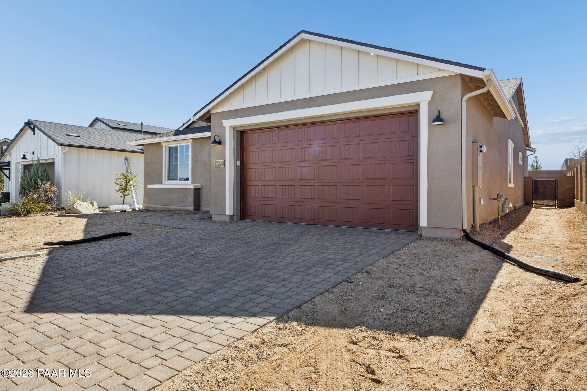 Modern 1-story Durango II B home with 3-car garage, red door, and paver driveway in Westwood, Prescott, Arizona