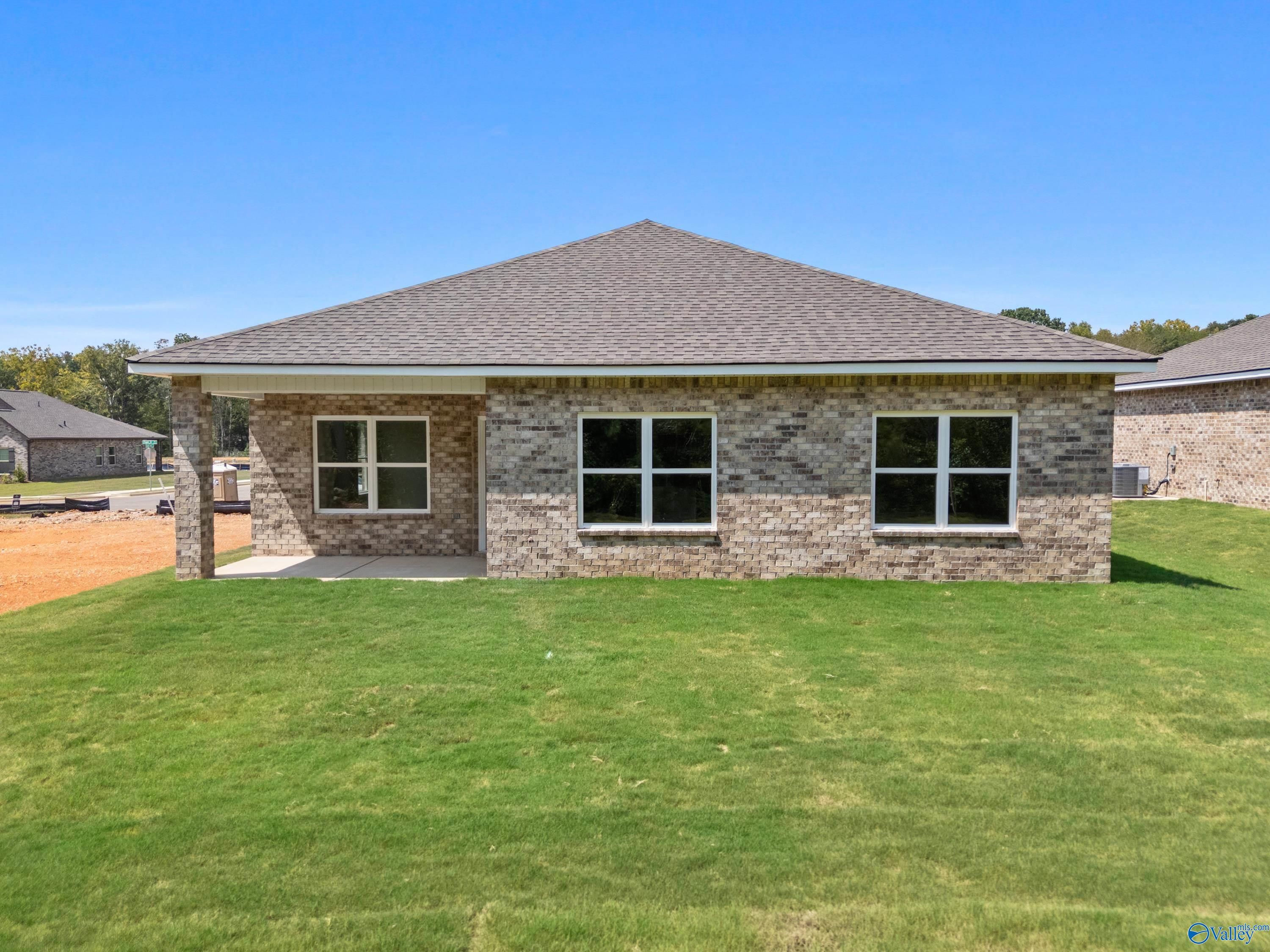 Single-story brick home with gabled roof, covered porch, garage doors, and lush green lawn in Spragins Cove, Huntsville, Alabama - Davidson Homes The Franklin
