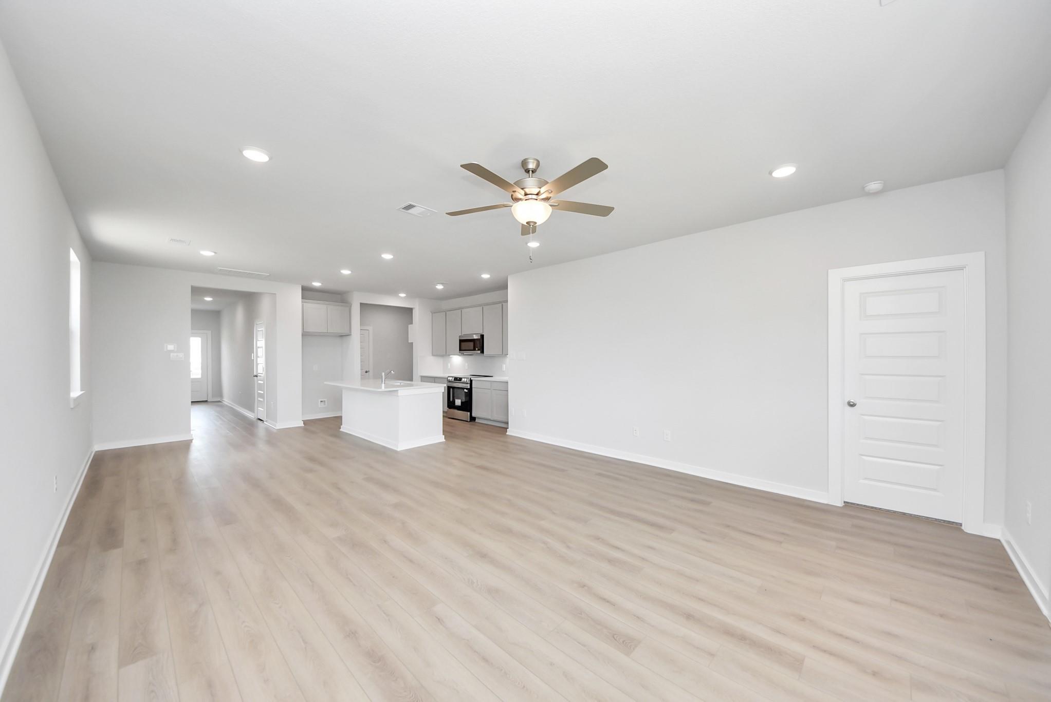 Open-concept living room and kitchen in The Blanco F floor plan at Spring Branch Crossing, Conroe, Texas.