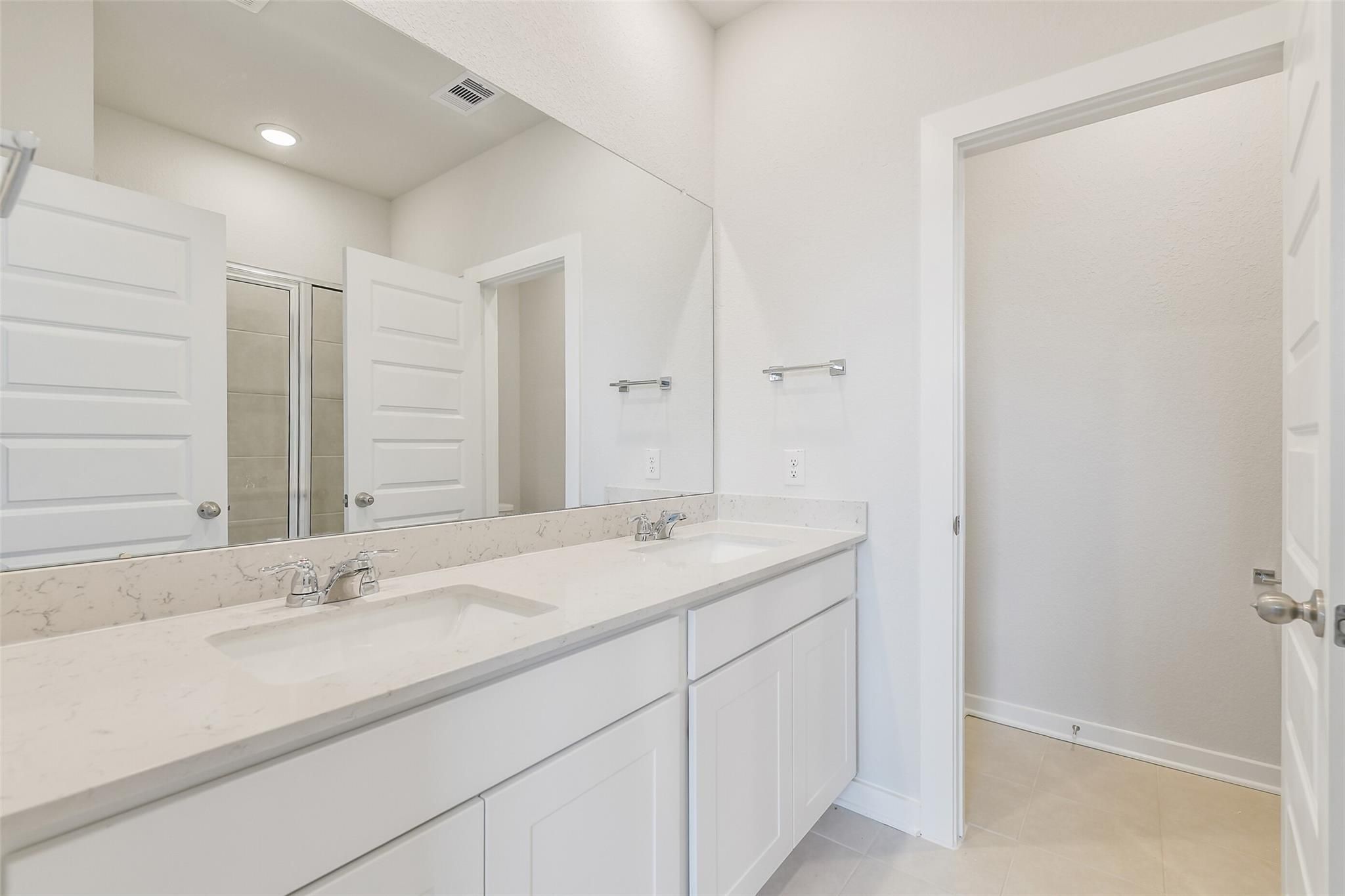Modern master bath double vanity with quartz counters, white cabinets, mirrors in Davidson Homes The Frio G, Cleveland Texas