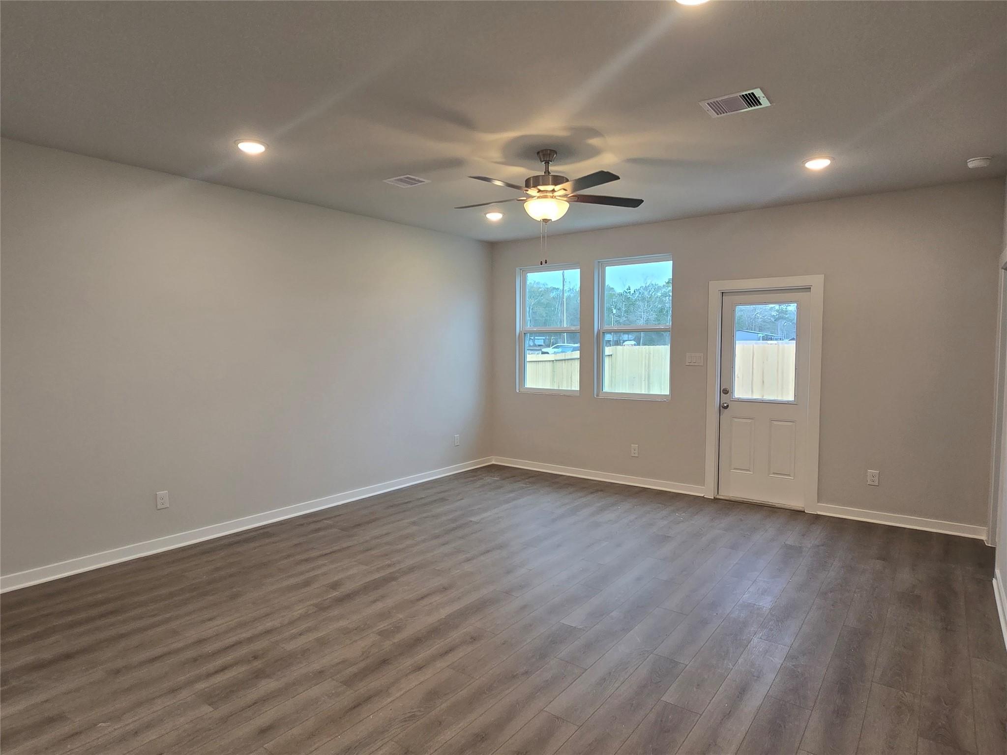 Bright master bedroom with ceiling fan, large windows, hardwood floors in Davidson Homes The Brazos E, Cleveland Texas