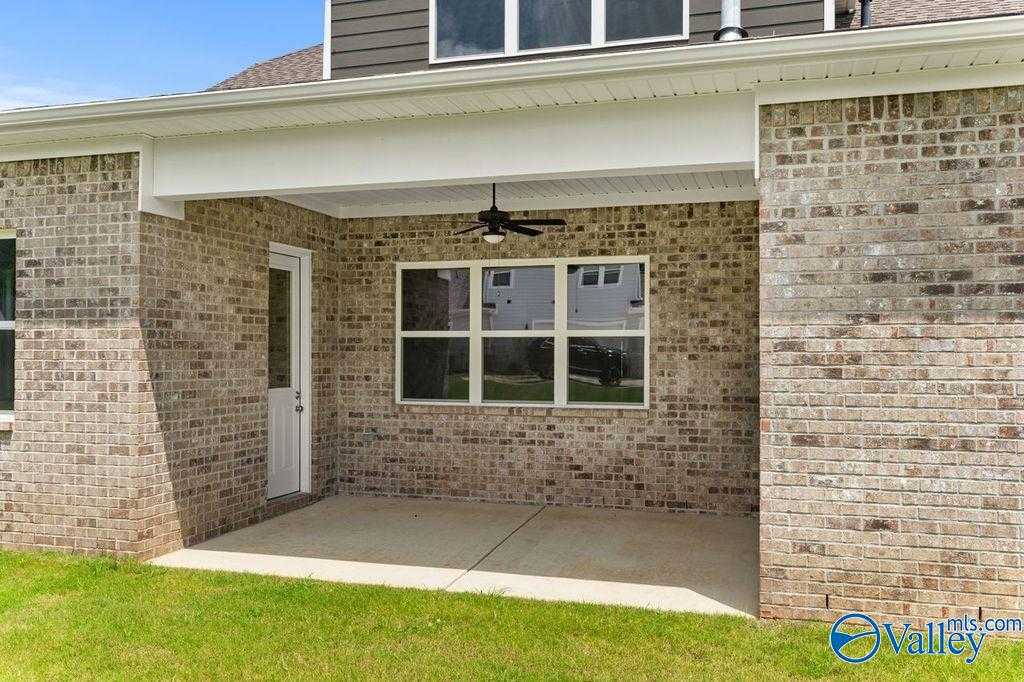Covered brick back patio with ceiling fan, large windows, and glass door in Evermore Homes The Oxford, Owens Cross Roads, Alabama