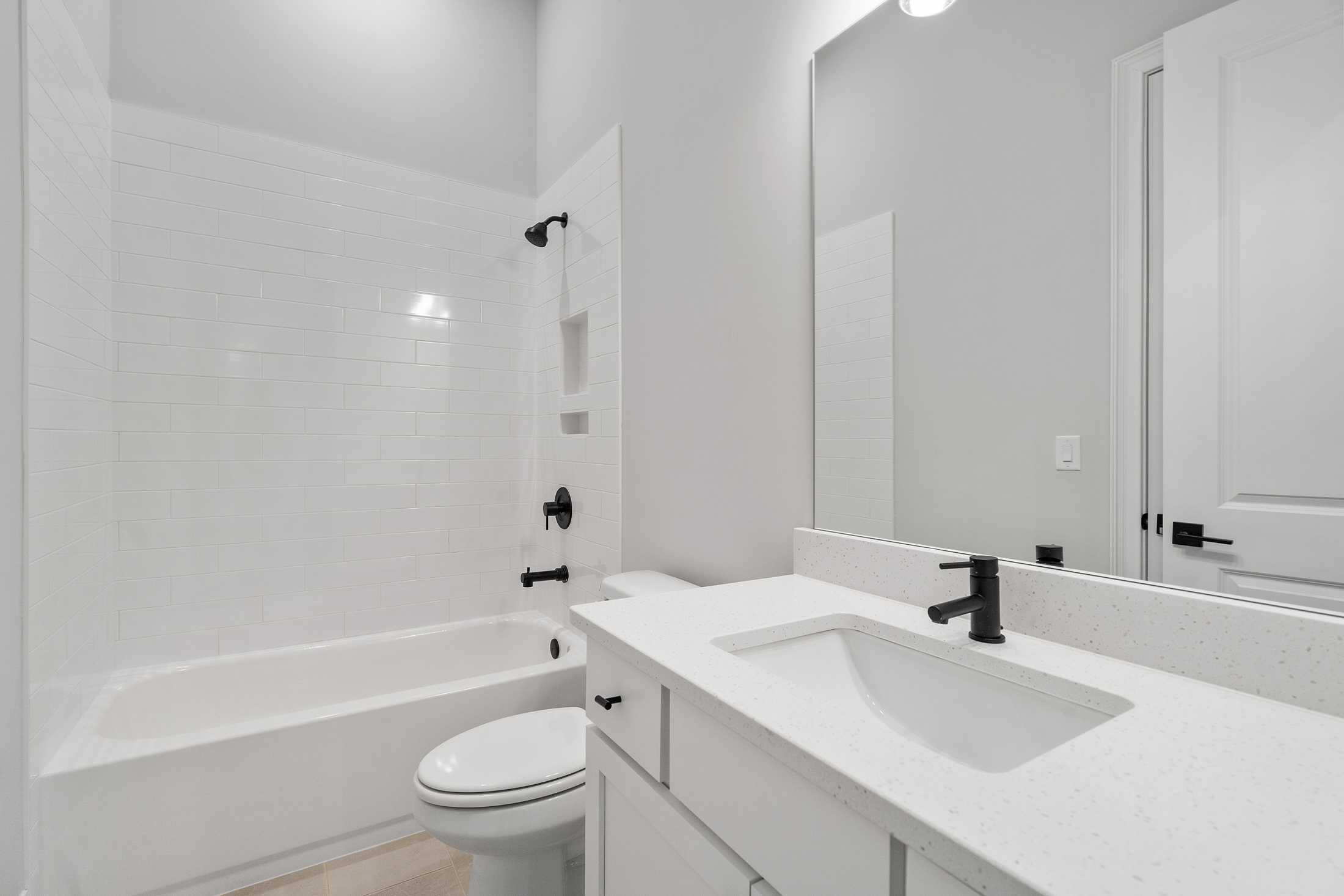 Modern bathroom in The Seaside by Davidson Homes featuring white subway tile shower, tub combo, single sink vanity, and large mirror