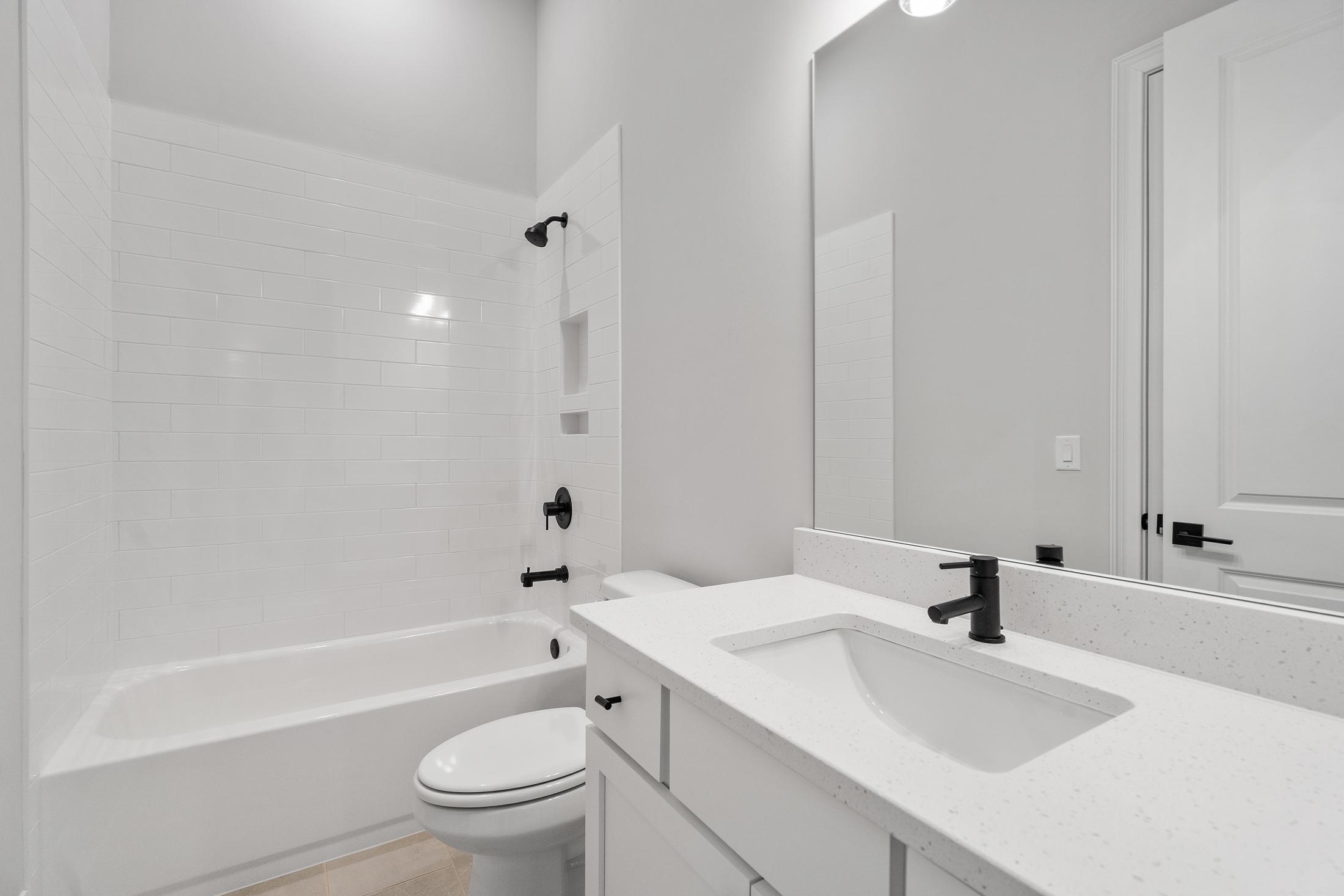 Modern bathroom in The Seaside by Davidson Homes featuring white subway tile shower, tub combo, single sink vanity, and large mirror
