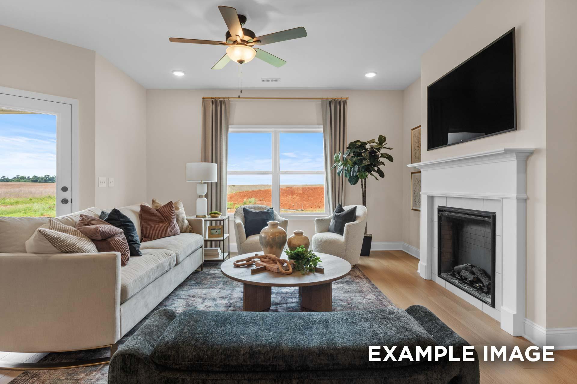 Spacious living room in The Laurel M showcasing neutral tones, large windows with field views, white fireplace, and plush beige sofa