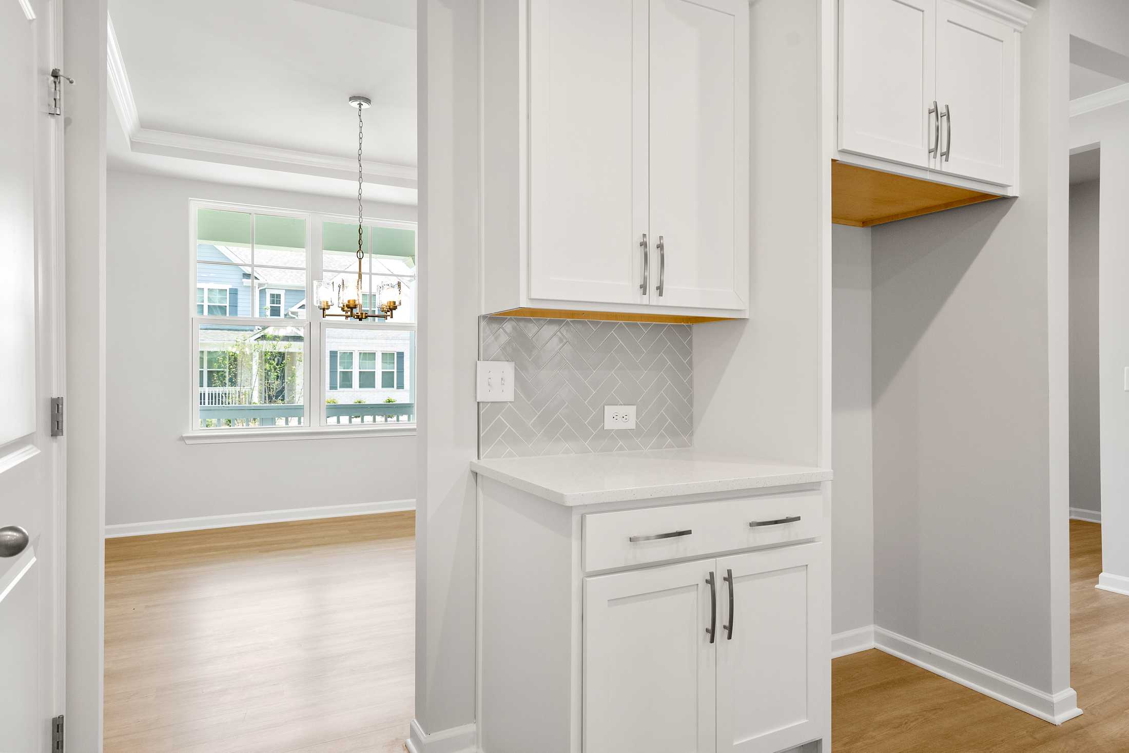 Modern kitchen in The Ash B at Wehunt Meadows featuring white shaker cabinets, gray subway tile backsplash, and open wood shelving