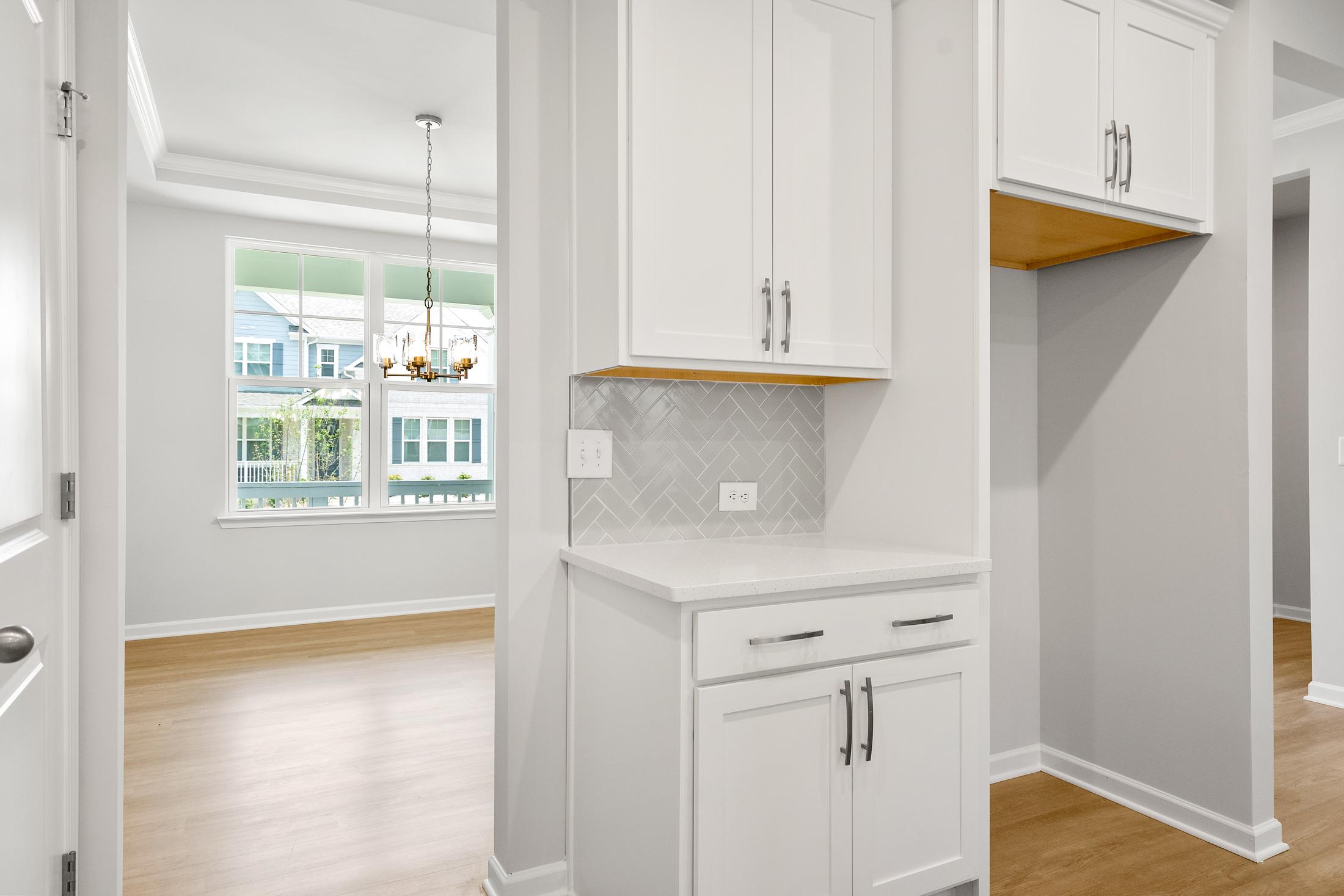 Modern kitchen in The Ash B at Wehunt Meadows featuring white shaker cabinets, gray subway tile backsplash, and open wood shelving