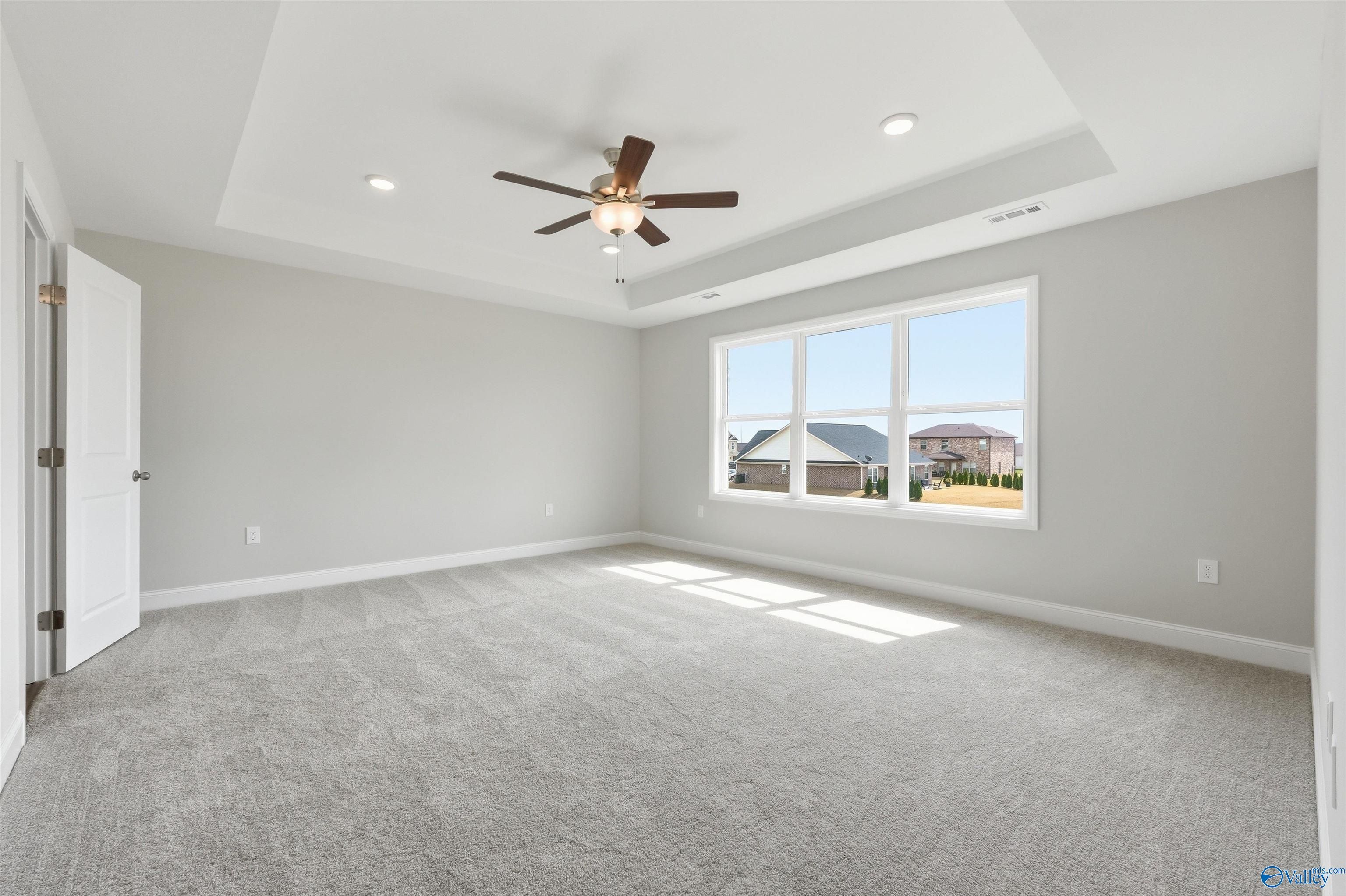 Spacious bedroom with tray ceiling and ceiling fan in The Shelby D floor plan at Evergreen Mill in Madison, Alabama.