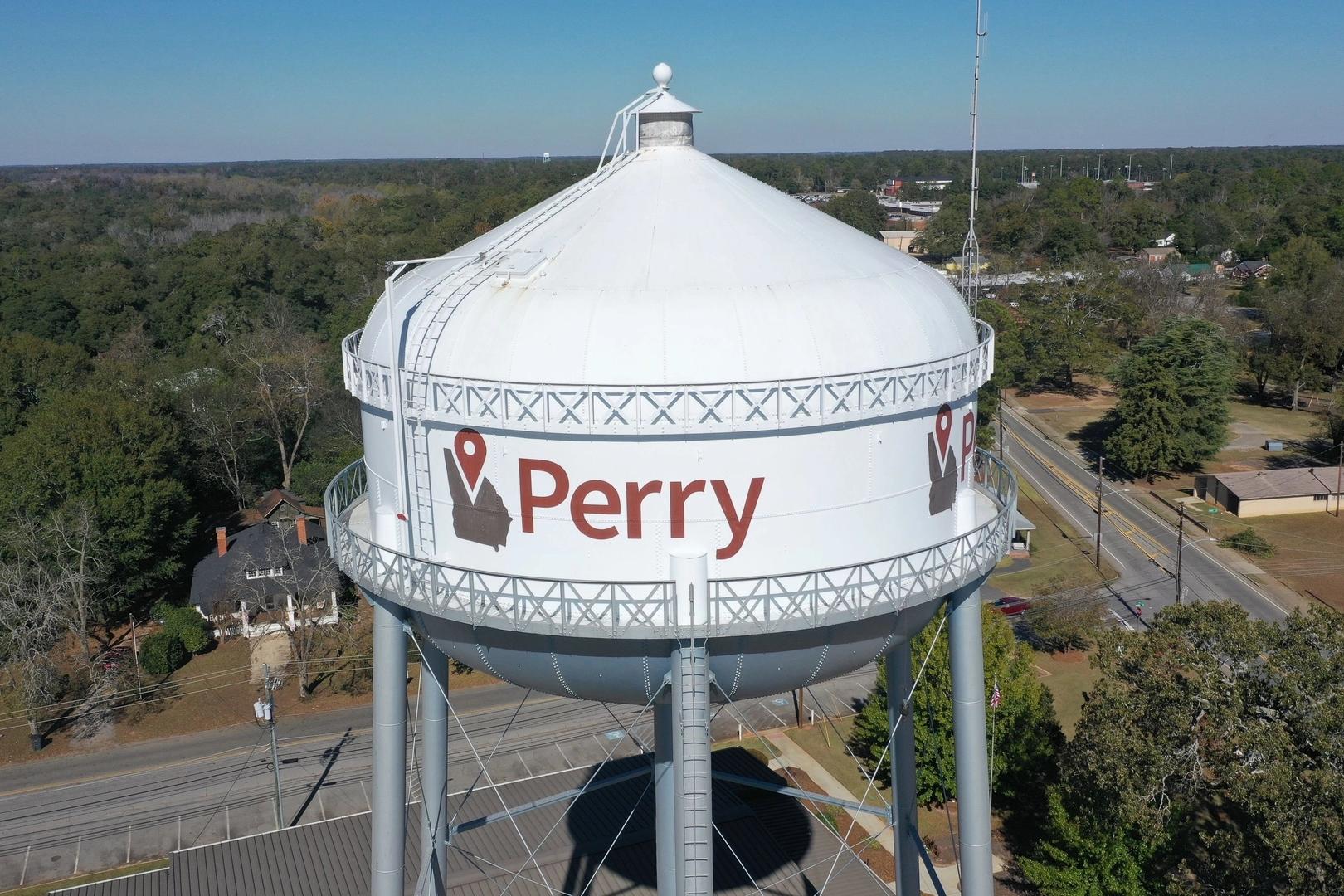 Perry Georgia water tower landmark with red logo, aerial view of pines, roads, and suburban homes