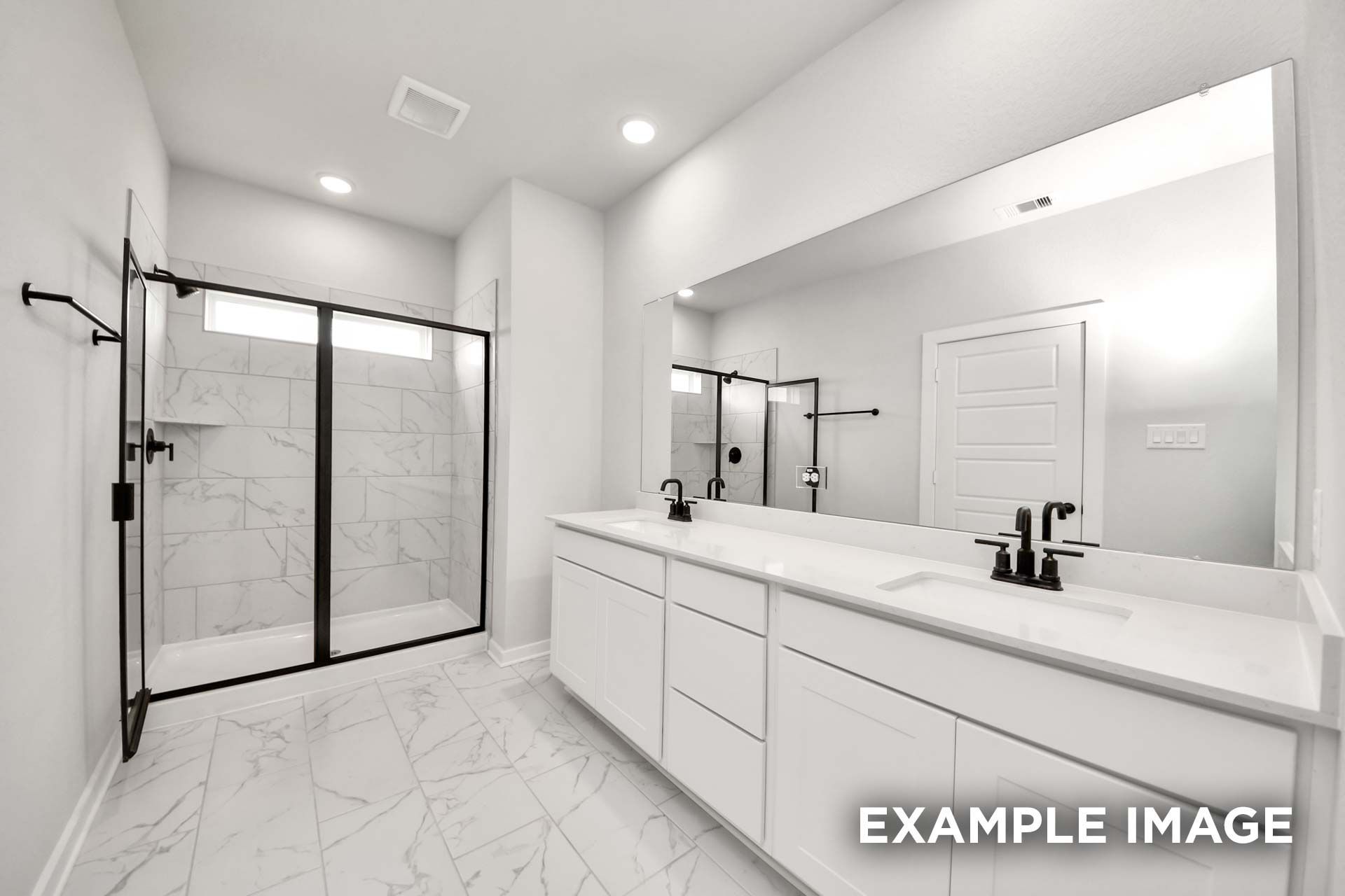 Modern master bathroom in The Sorrento featuring a white dual vanity, marble-style tile, and glass-enclosed walk-in shower.