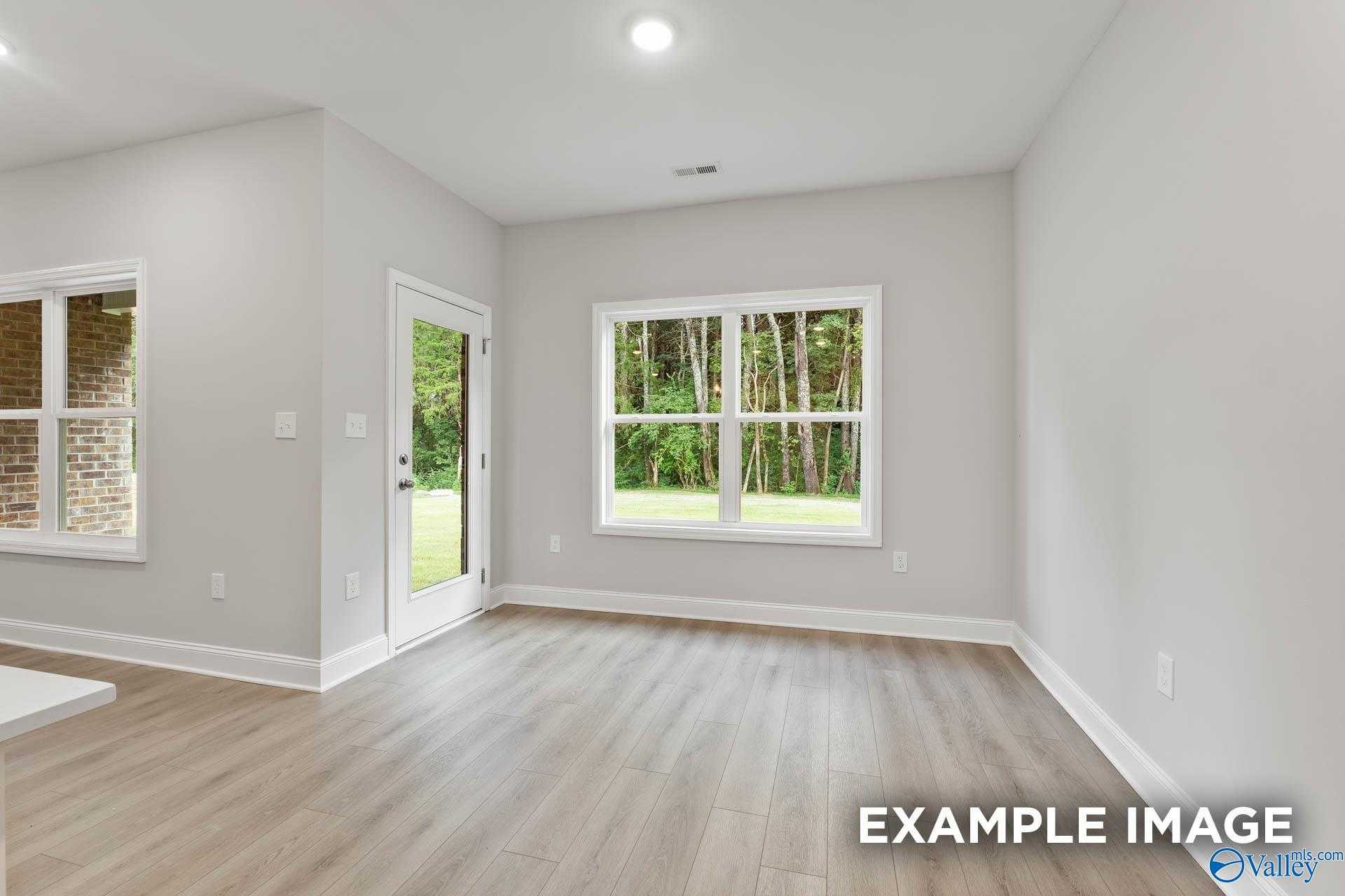 Bright family room with light gray walls, large windows, French doors to wooded backyard in Davidson Homes The Asheville C, Huntsville AL