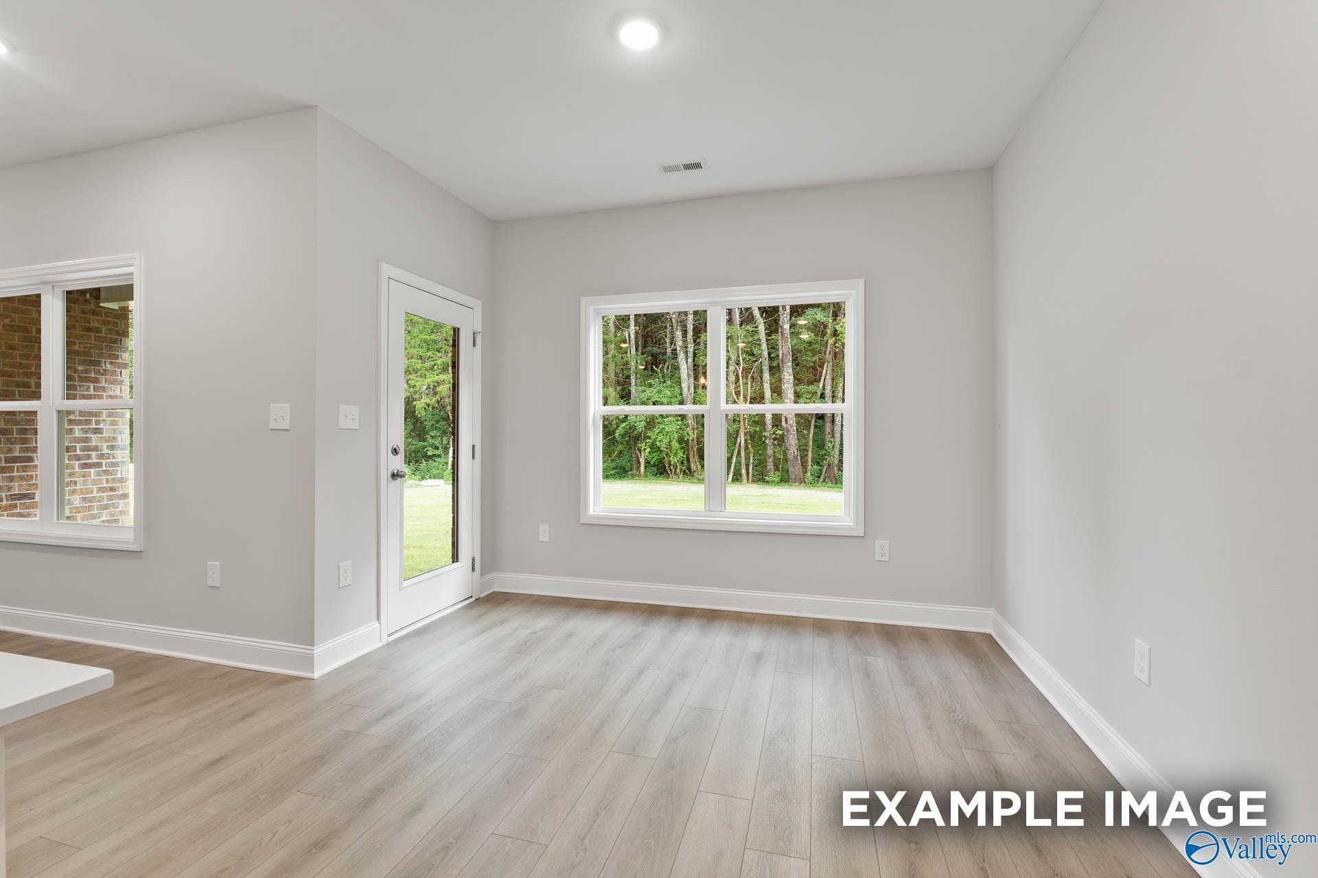 Bright living room with large windows and French door overlooking wooded backyard in The Asheville by Davidson Homes, Huntsville AL