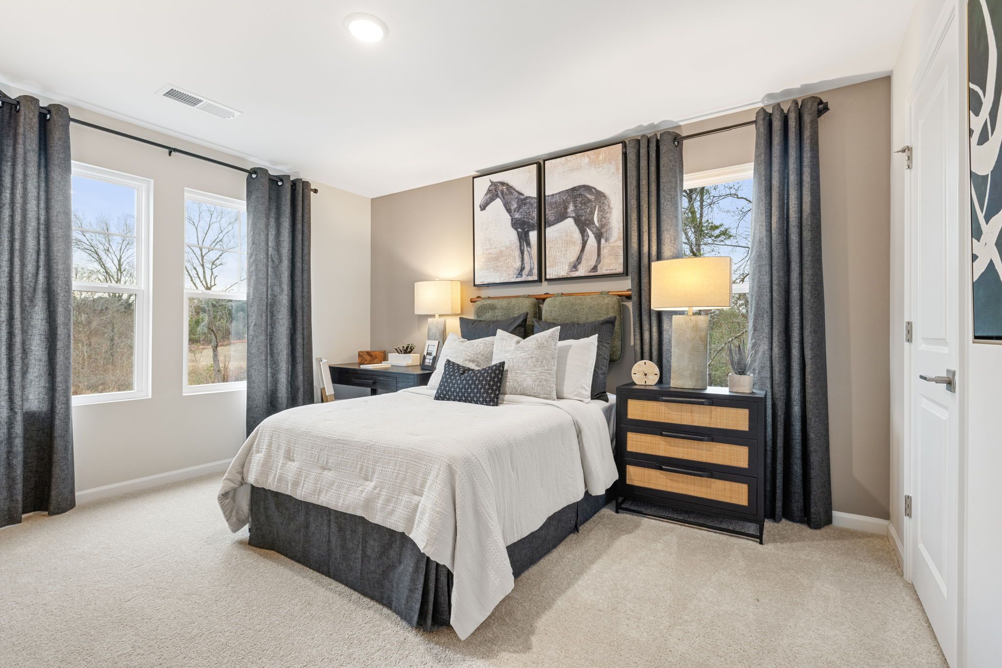 Cozy bedroom at Lake Shore in Winder GA by Davidson Homes with queen bed, equestrian art, gray curtains, and neutral tones