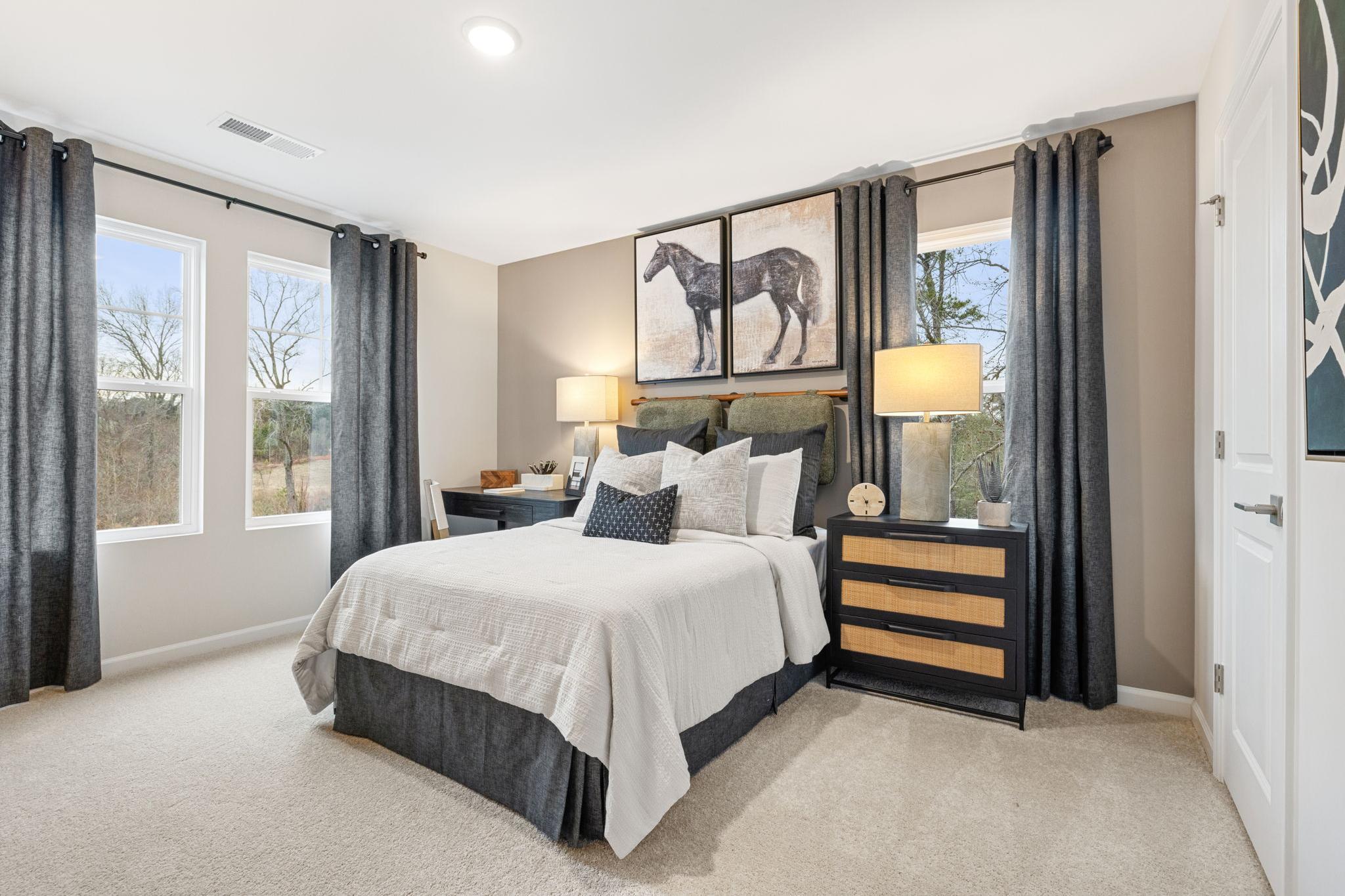 Cozy bedroom at Lake Shore in Winder GA by Davidson Homes with queen bed, equestrian art, gray curtains, and neutral tones