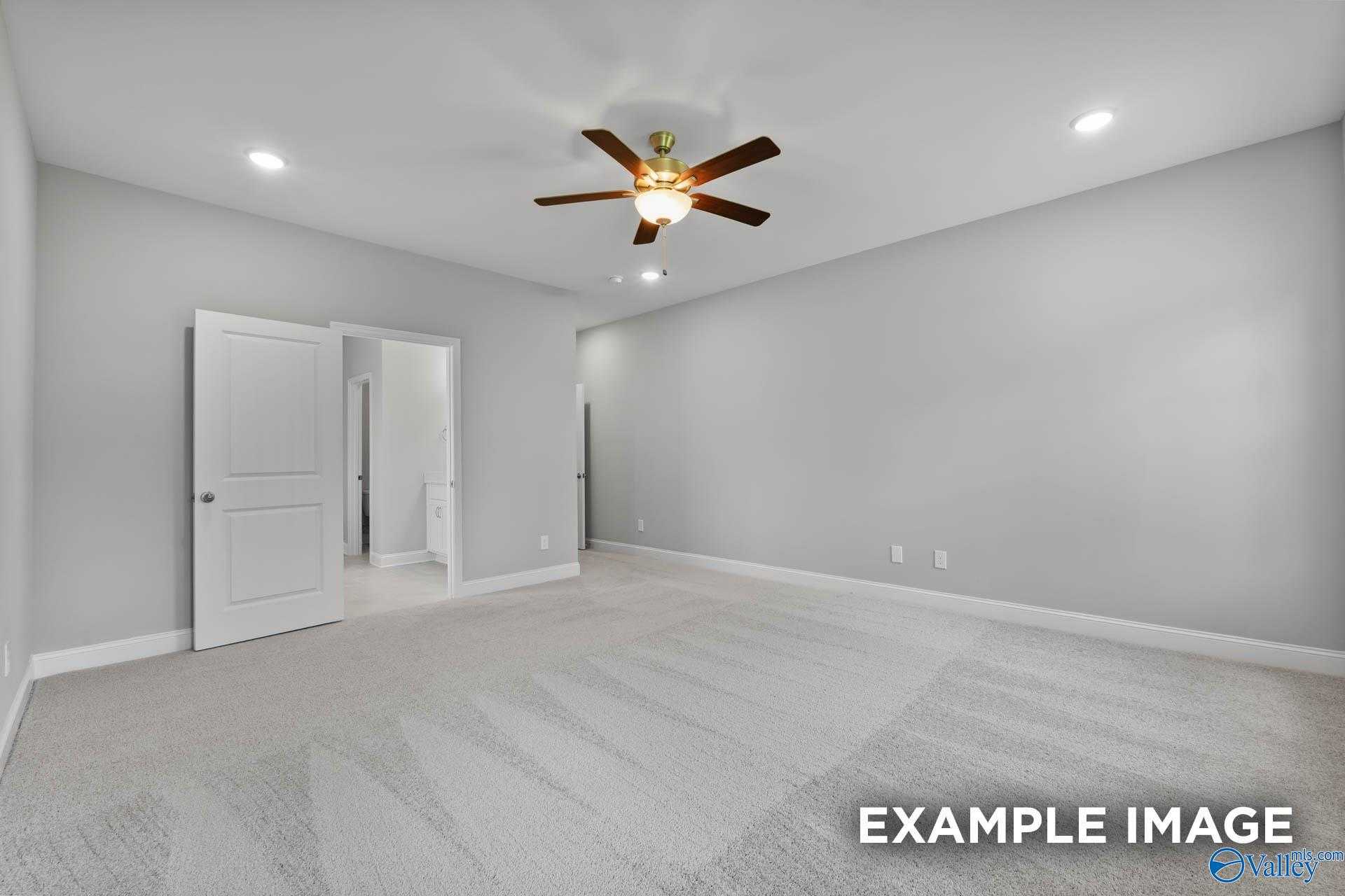 Spacious bedroom with gray walls, carpeted floors, ceiling fan, and open double doors in Davidson Homes The Rockford D, Hazel Green, Alabama