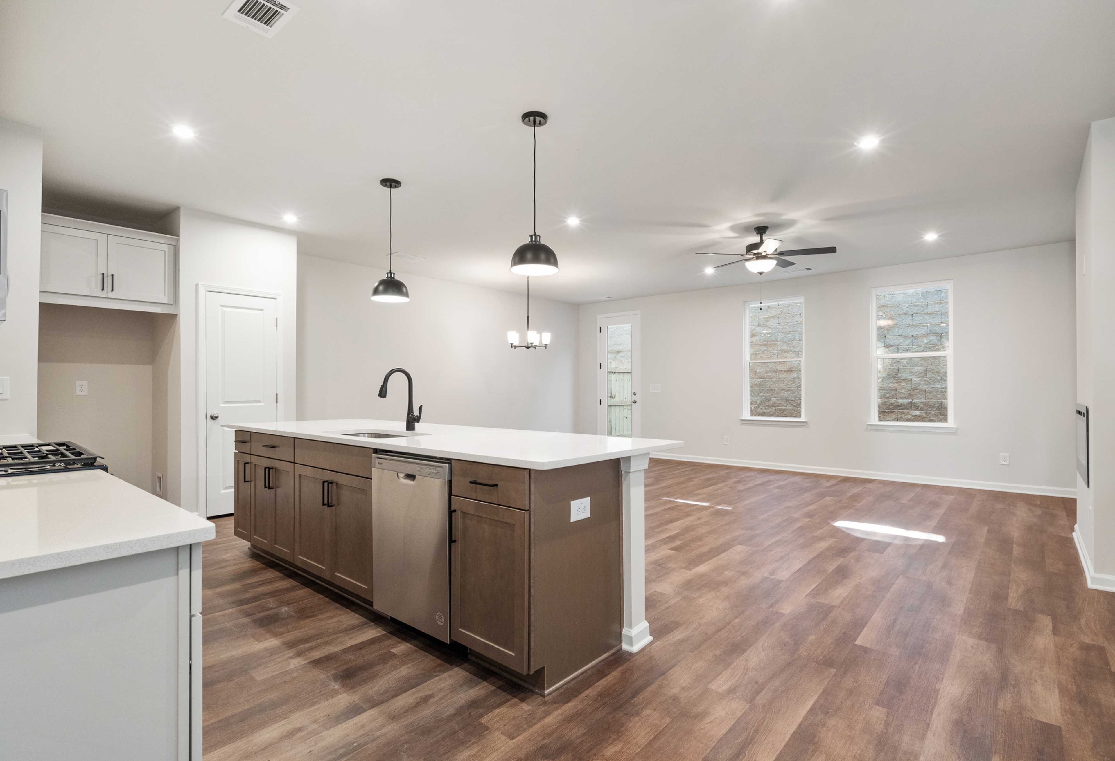 Modern kitchen in The Cary B by Davidson Homes featuring large quartz island, pendant lights, and open living area