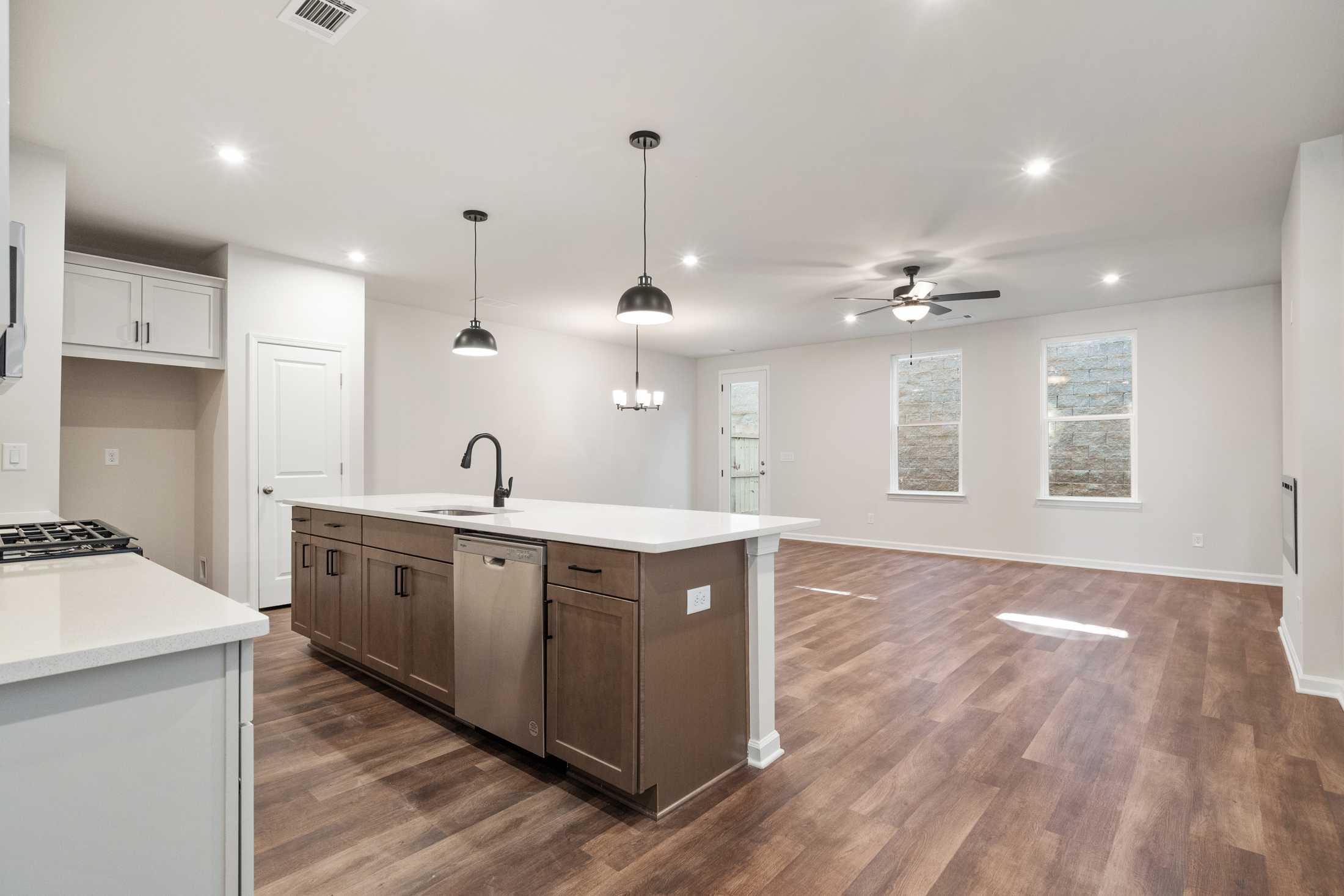 Modern kitchen in The Cary B by Davidson Homes featuring large quartz island, pendant lights, and open living area