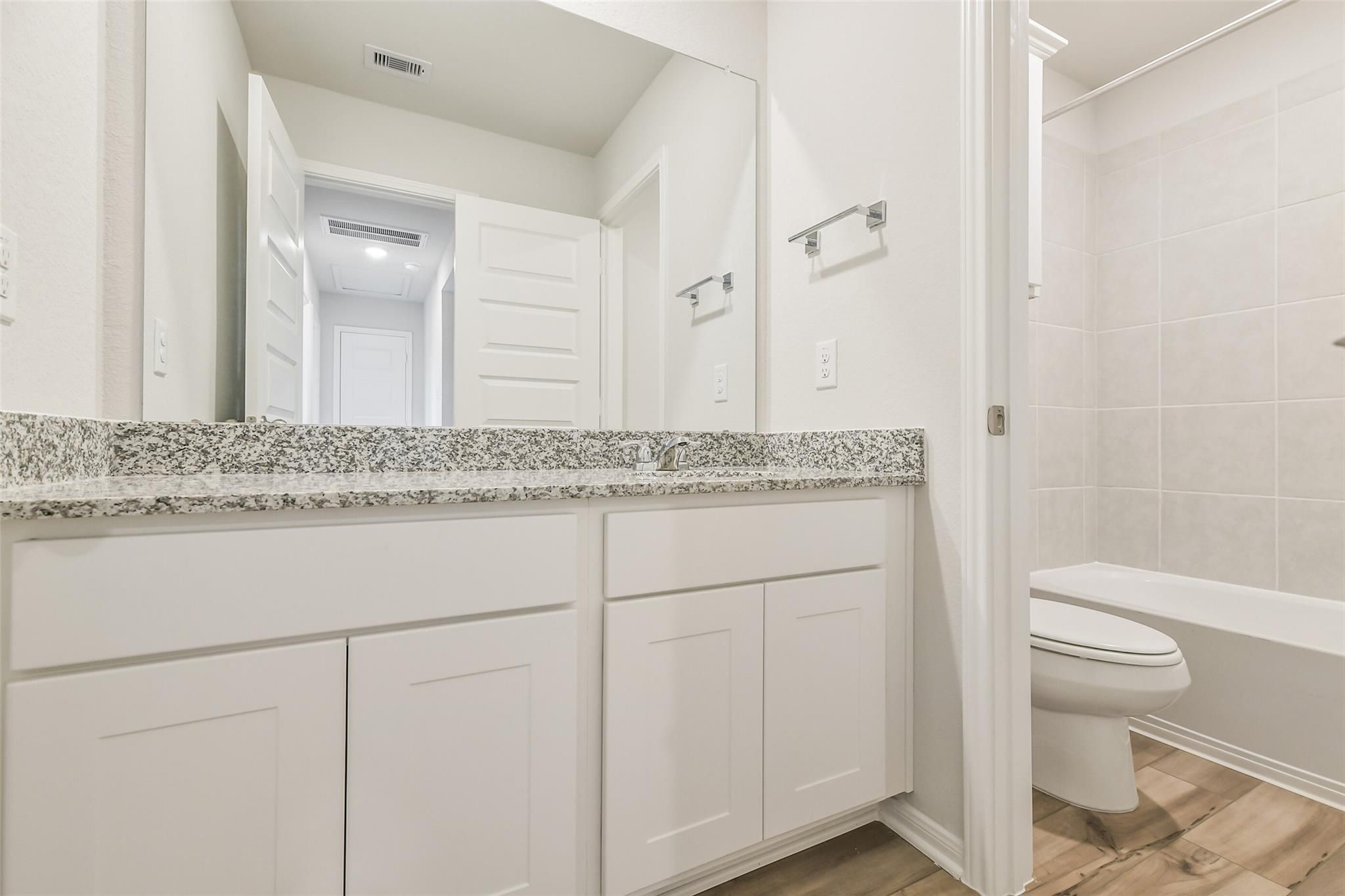 Modern bathroom featuring double white vanity, granite countertop, large mirror, subway tile walls in The Brazos F by Davidson Homes, Conroe, TX