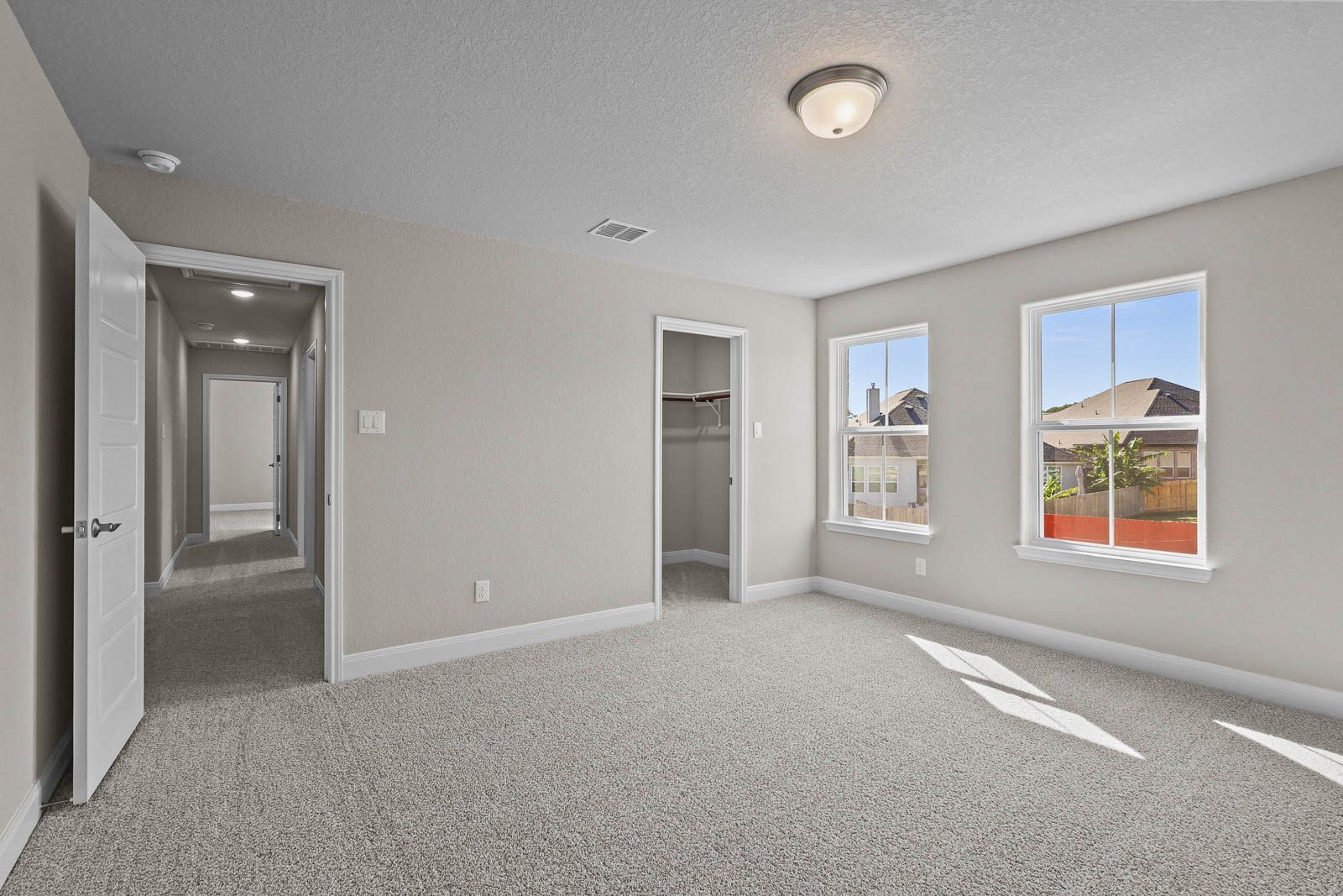 Spacious bedroom in The Jennings G featuring plush carpeting, walk-in closet, and natural light in Castroville, Texas.