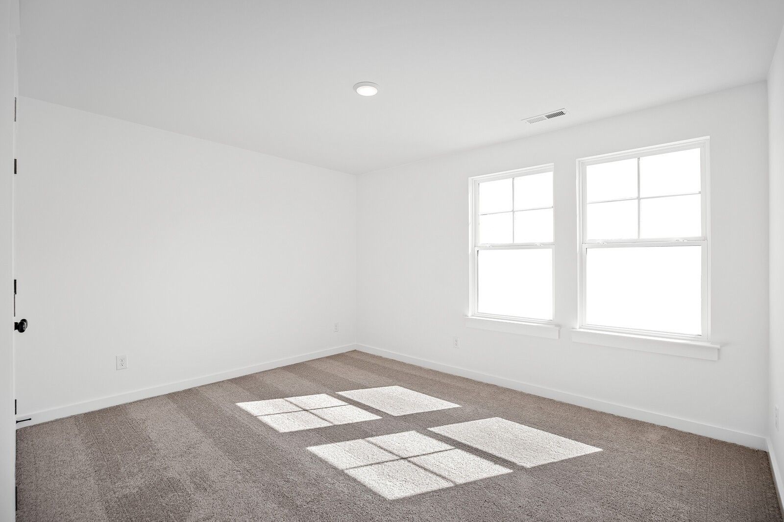Bright sunlit bedroom with white walls, double windows, and beige carpet in The Logan C 3-bedroom home, Gallatin, Tennessee