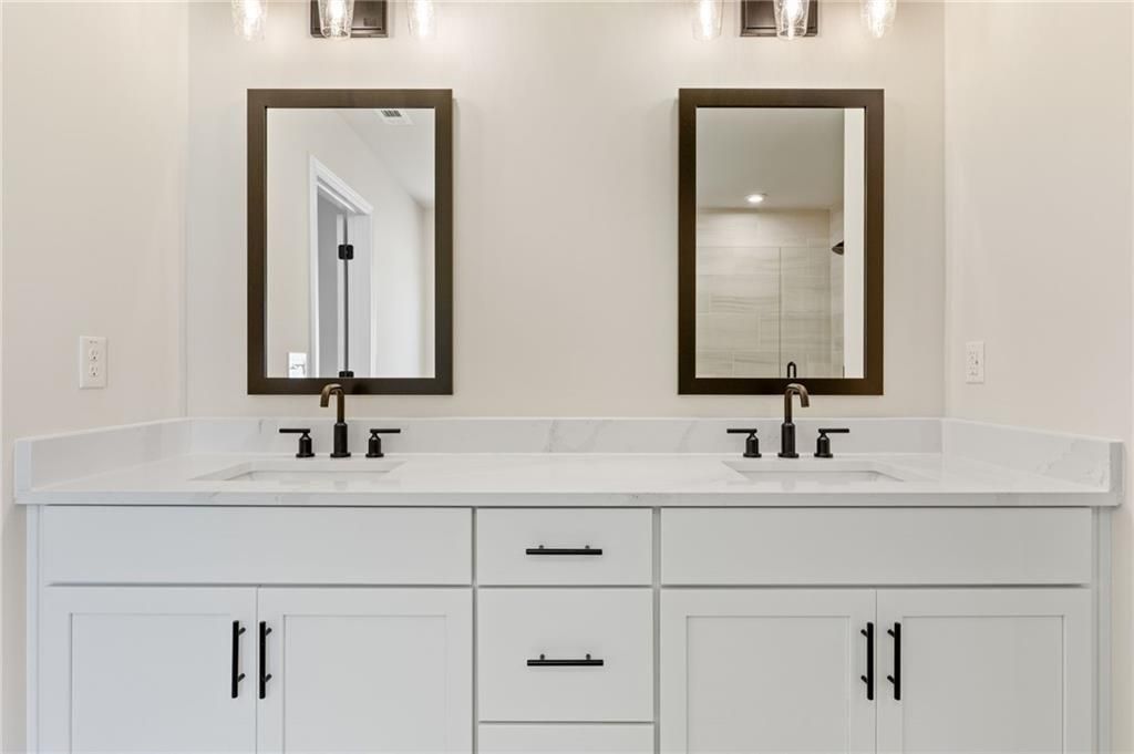 Elegant master bath double vanity with marble counters, black faucets, and framed mirrors in The Hickory E by Davidson Homes, Buford, Georgia