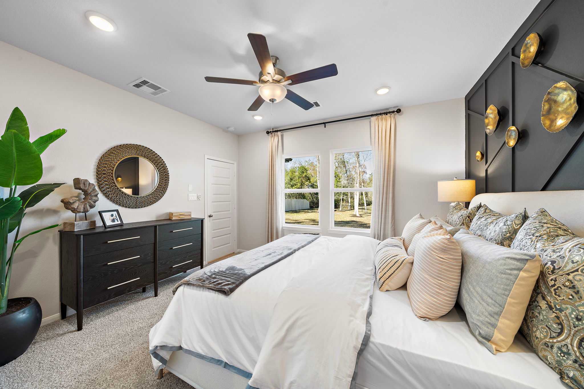 Spacious primary bedroom at Lakes at Black Oak in Magnolia Texas with king bed ceiling fan and accent wall