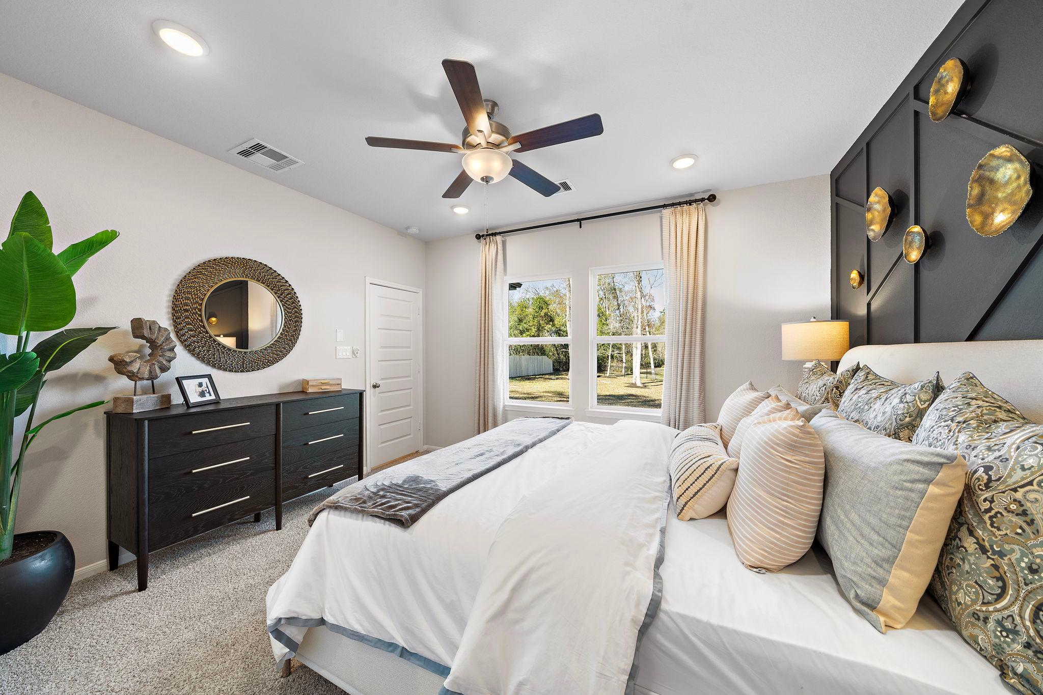 Spacious primary bedroom at Lakes at Black Oak in Magnolia Texas with king bed ceiling fan and accent wall