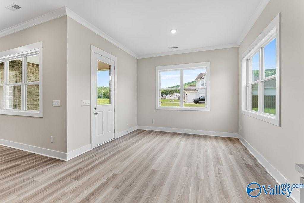 Bright sunroom with large windows, hardwood floors and patio door in Evermore Homes The Oxford, Owens Cross Roads, Alabama