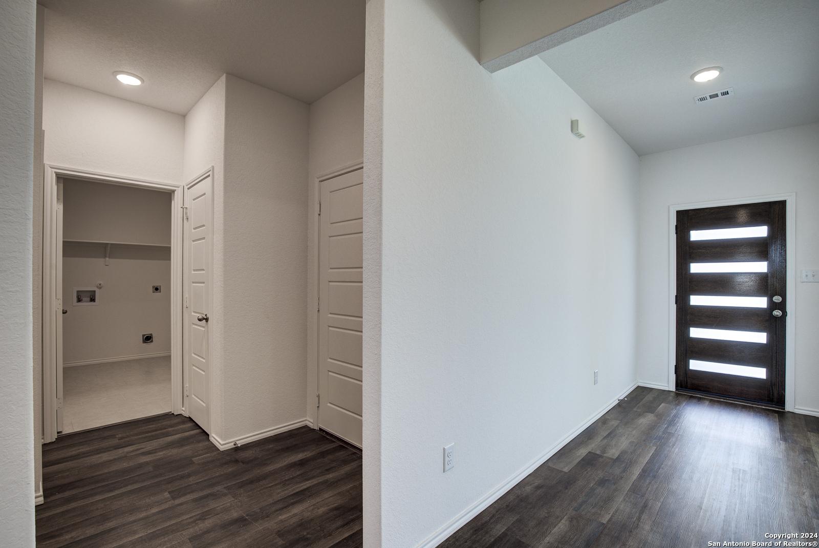 Modern laundry room with utility sink and adjacent entry foyer featuring frosted glass door in The Douglas D, Seguin, Texas