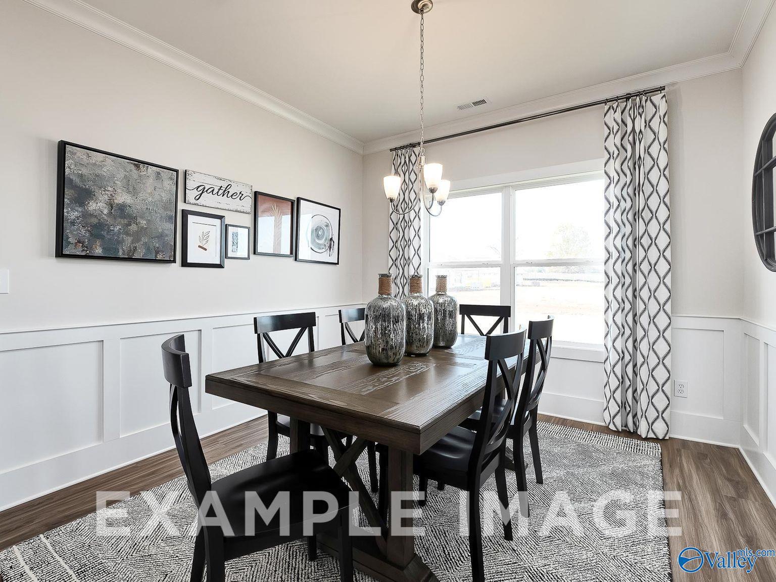Elegant dining room featuring wooden table with vases, chandelier, and wall art in The Everett B 4-bedroom home, Toney, Alabama