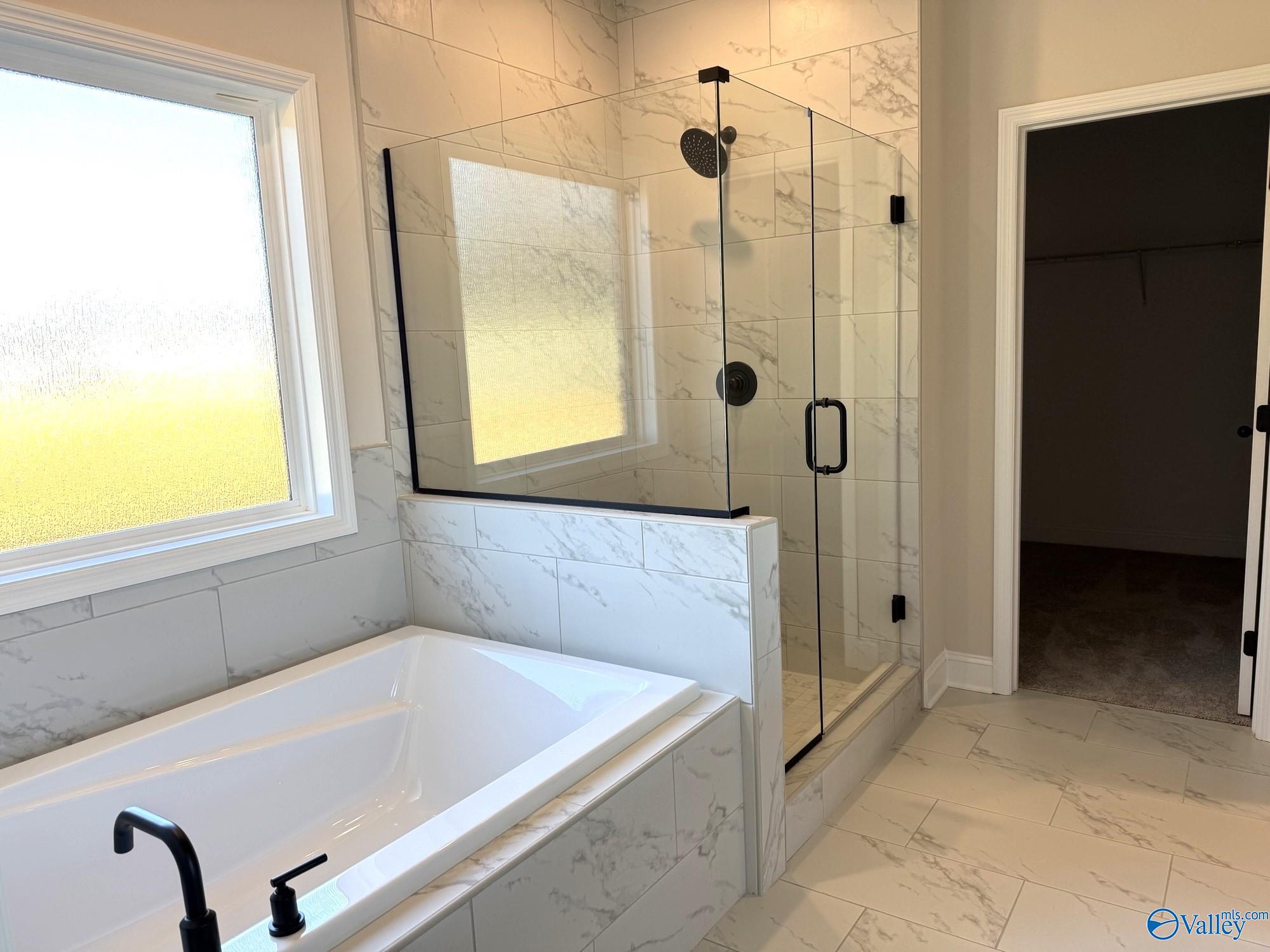 Modern master bathroom featuring frameless glass shower and soaking tub in Davidson Homes The Rockford B, Hartselle, Alabama