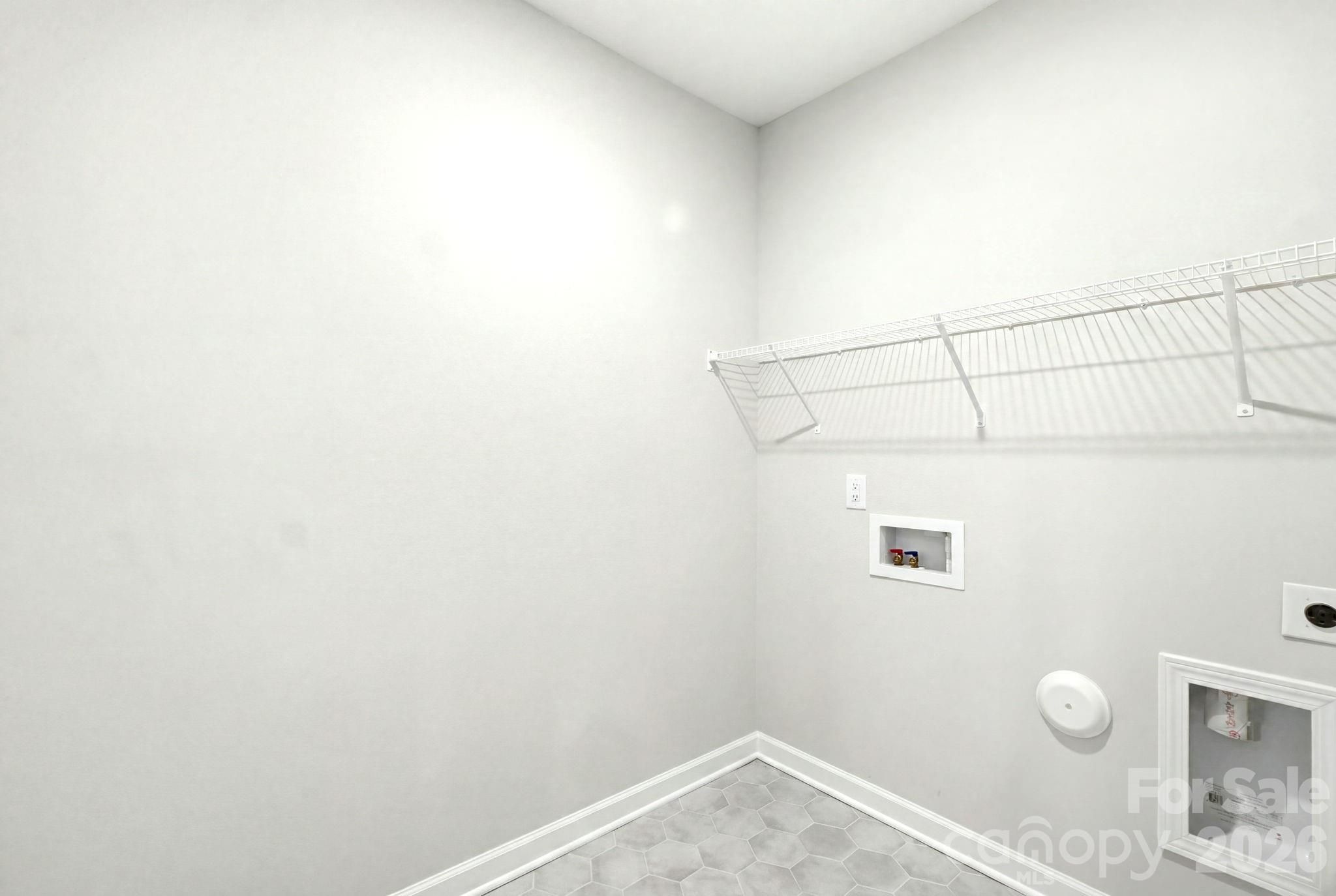 Laundry room with wire shelving and utility hookups in a Davidson Homes Magnolia B floor plan in Windgate, Mooresville.