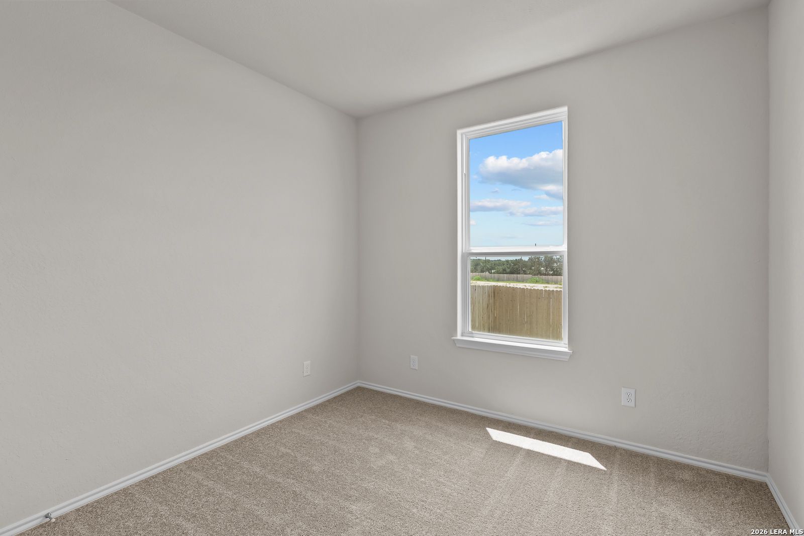 Bright, carpeted bedroom with large window in The Gillian B floor plan at Meadows at Oak Creek, San Antonio, Texas.
