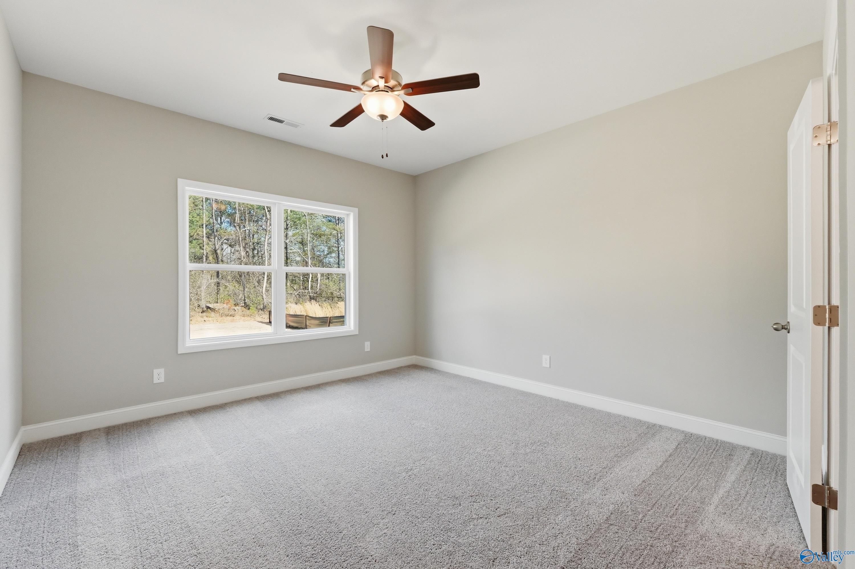 Bright secondary bedroom with large window, ceiling fan, neutral walls, and carpet in The Asheville floor plan, Spragins Cove, Huntsville