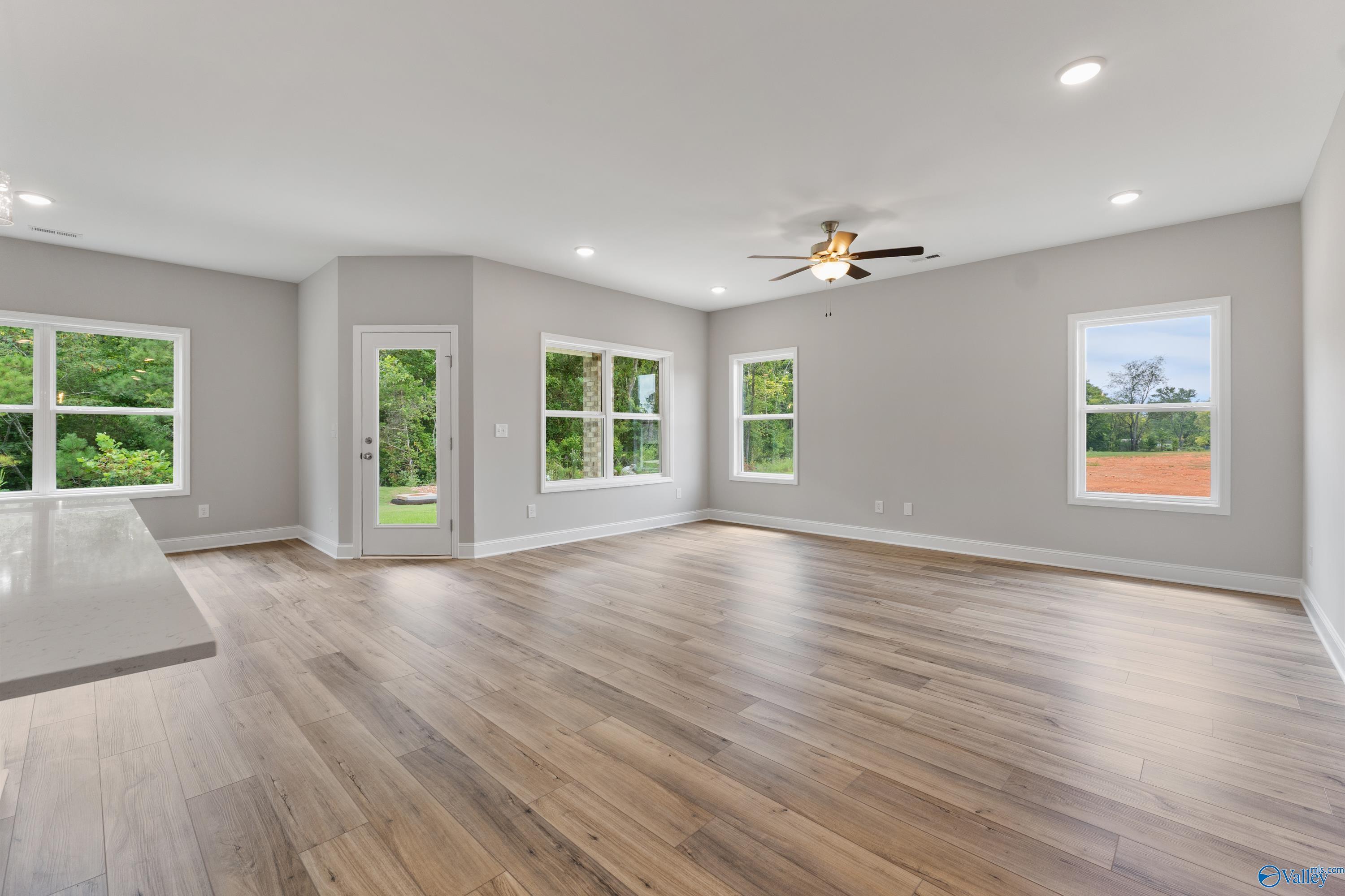 Bright open-concept living room with hardwood floors, large windows, and ceiling fan in Davidson Homes The Franklin, Huntsville, AL