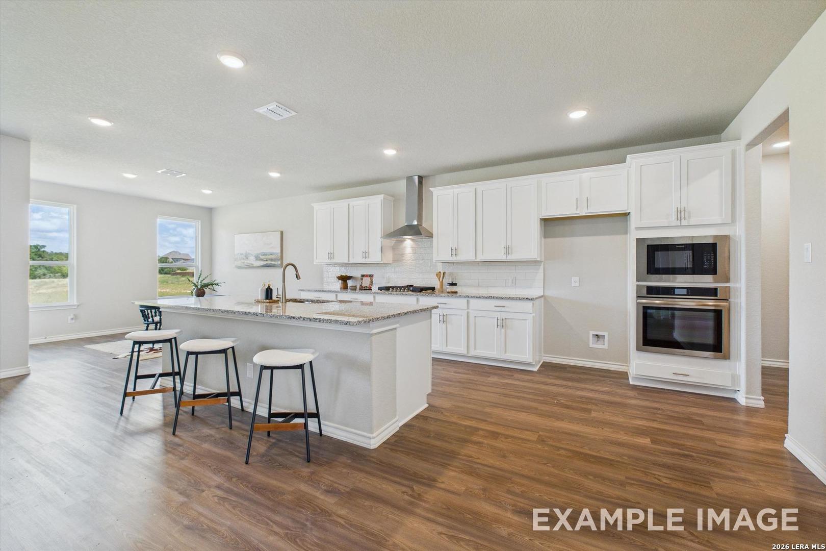 Modern kitchen with white cabinets, granite island, and stainless steel appliances in Davidson Homes Foster F floor plan.