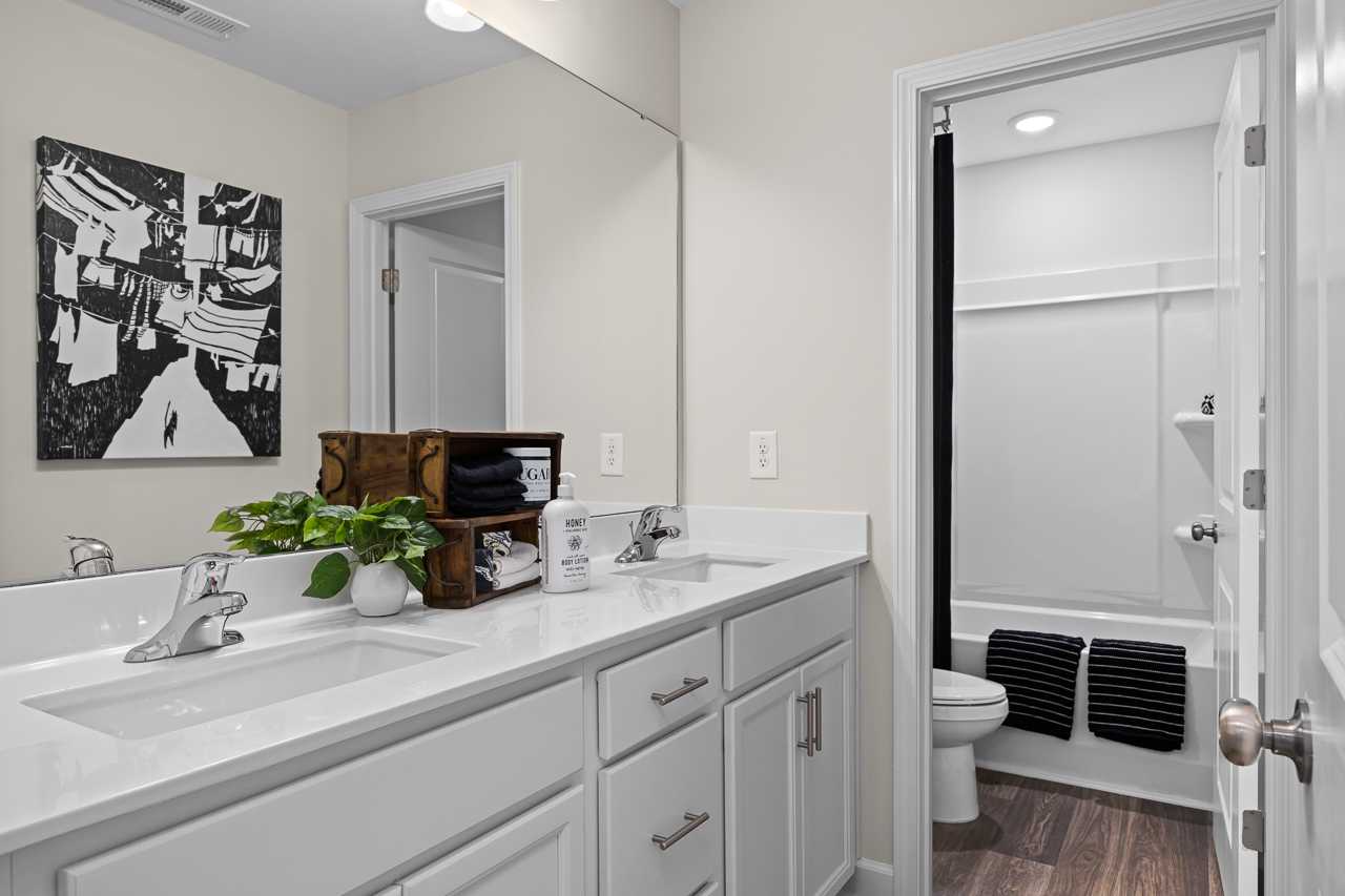 Spacious modern bathroom at Wellers Knoll in Lillington NC with white double vanity, soaking tub, and abstract art